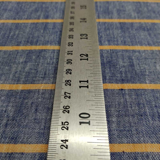 A perspective shot of a steel measuring scale lying blue cotton khadi fabric with orange stripes.