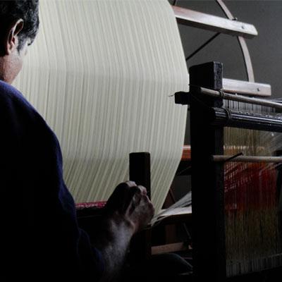 weaver sitting next to a warping drum and preparing a khadi warp for further cotton fabric weaving