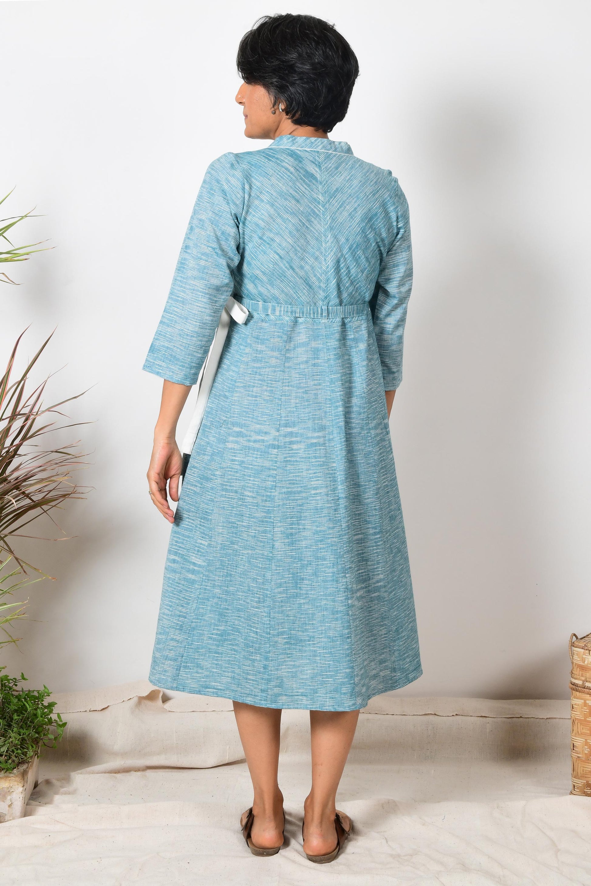 Back of an Indian women wearing blue cotton wrap around dress made with handspun cotton yarn.