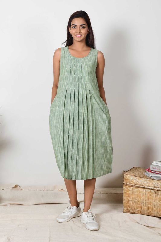 Smiling Indian girl wearing a handspun cotton green sleeveless pleated dress.a