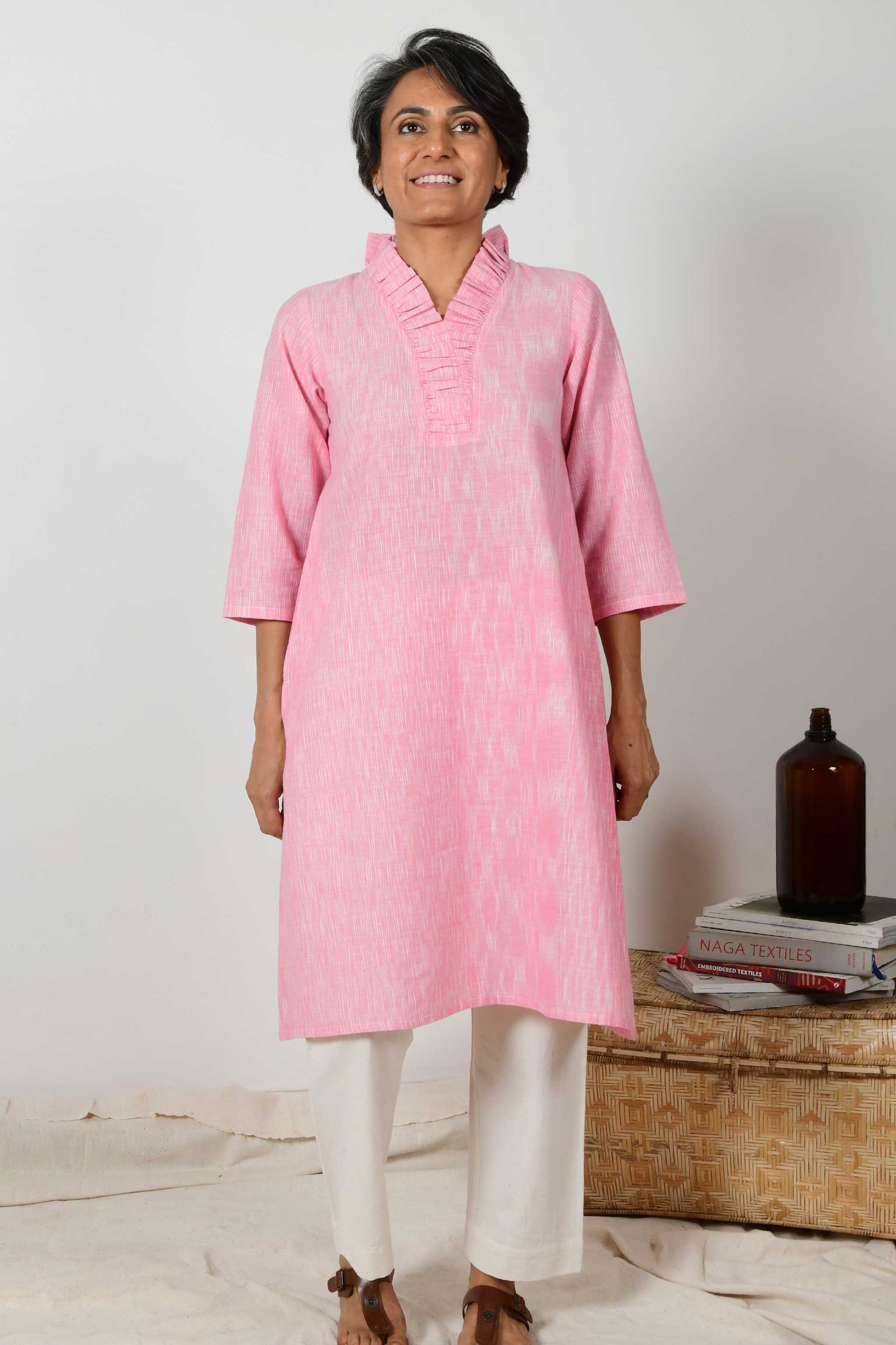 short haired indian woman wearing baby pink flared neck Kurta dress made using hand spun hand woven cotton.