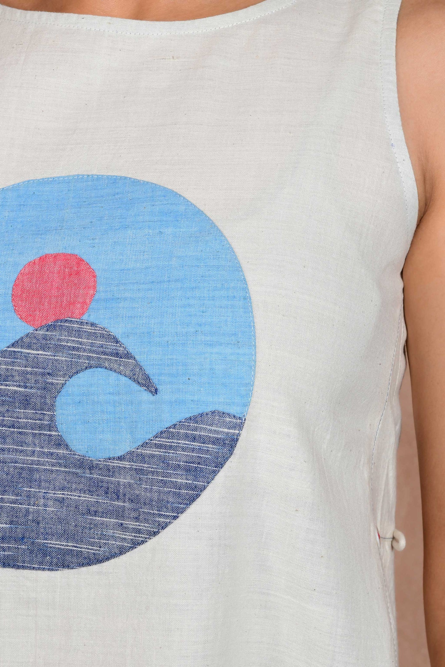Partial close up of an applique patch depicting a wave in the sea with a sun.