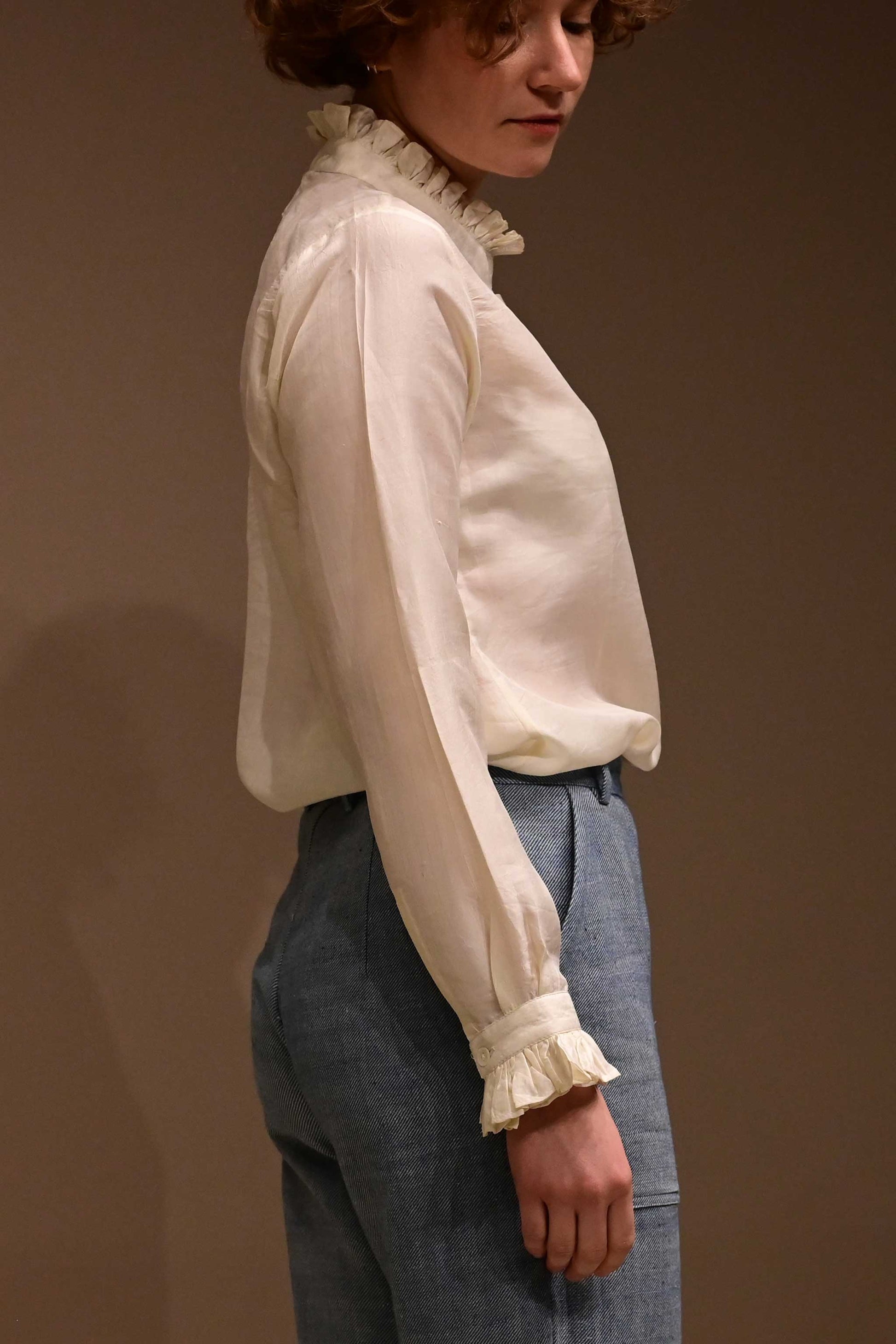 Side Profile of caucasian female model wearing white silk shirt that is hand reeled and hand spun in India.