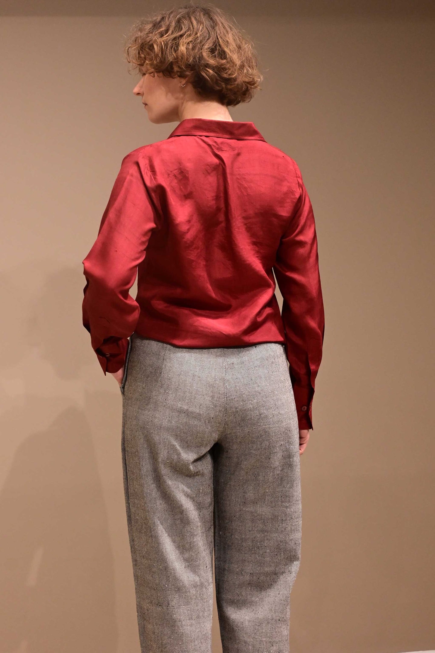 Back close up of a naturally dyed greyish black denims that is made if handspun and handwoven kala cotton from India. And of a wine red silk shirt for women.