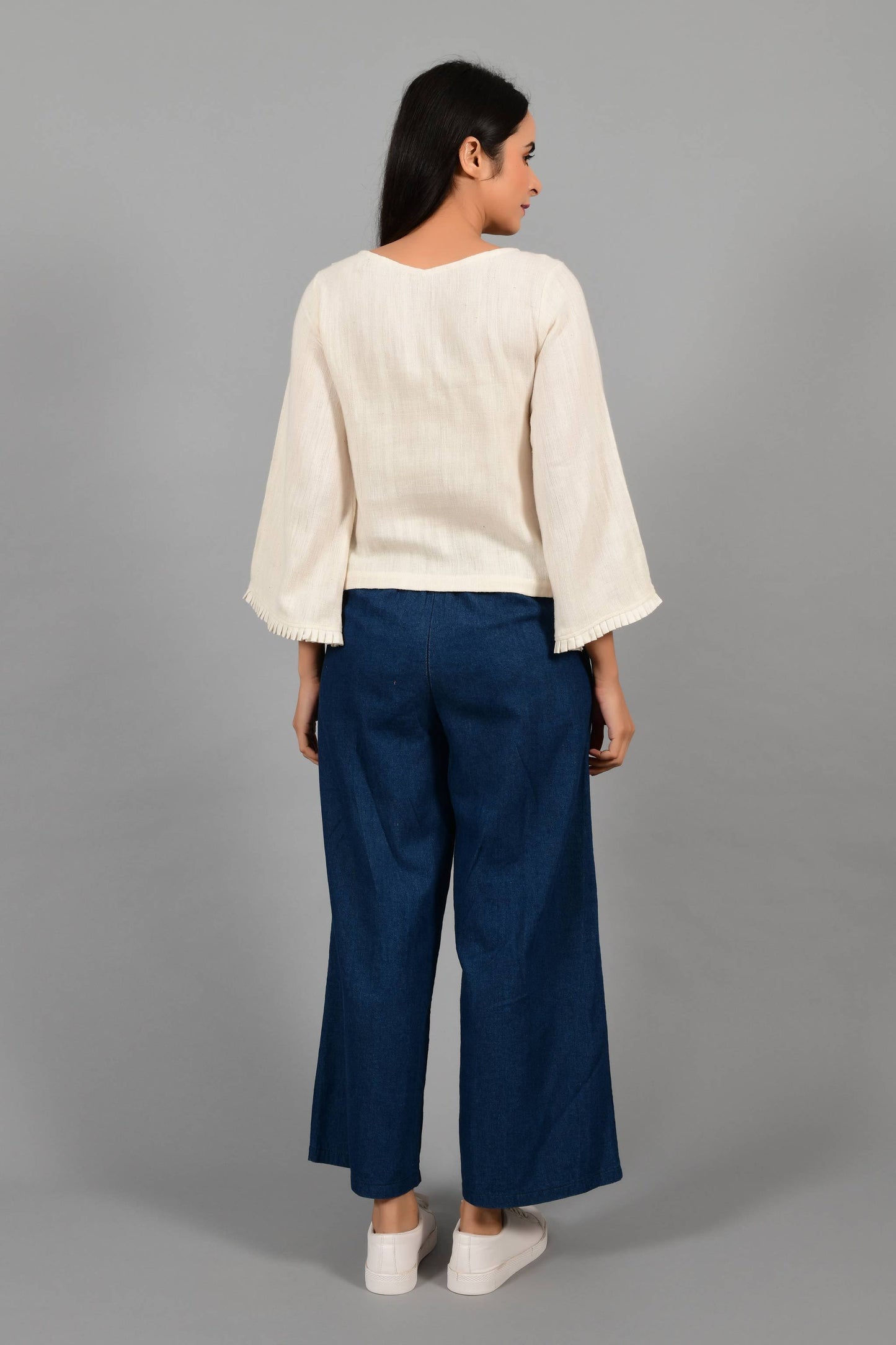 Back pose of an Indian female womenswear fashion model in an off-white Cashmere Cotton Top with bell sleeves made using handspun and handwoven khadi cotton by Cotton Rack.