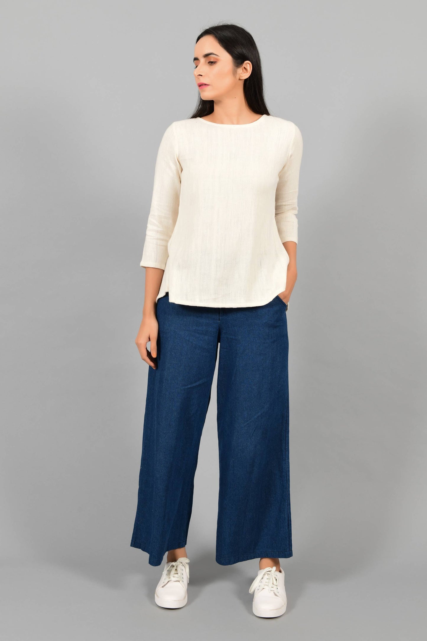 Front pose of an Indian female womenswear fashion model in an off-white Cashmere Cotton Top with box pleated back and quarter sleeves made using handspun and handwoven khadi cotton by Cotton Rack.