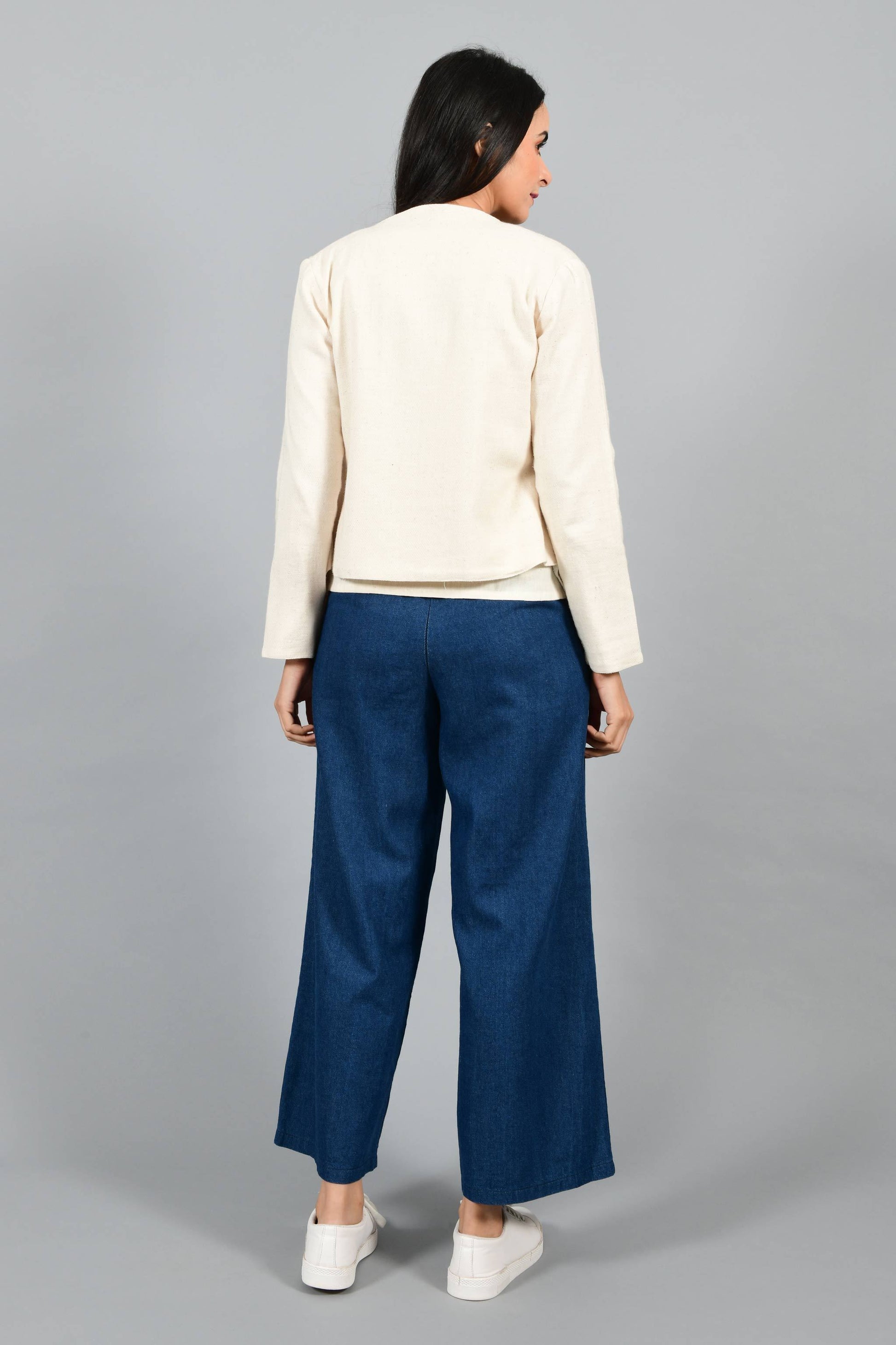 Back pose of an Indian female womenswear fashion model in a short off-white Cashmere Cotton jacket-shrug with extra wide lapels, made using handspun and handwoven khadi cotton by Cotton Rack.