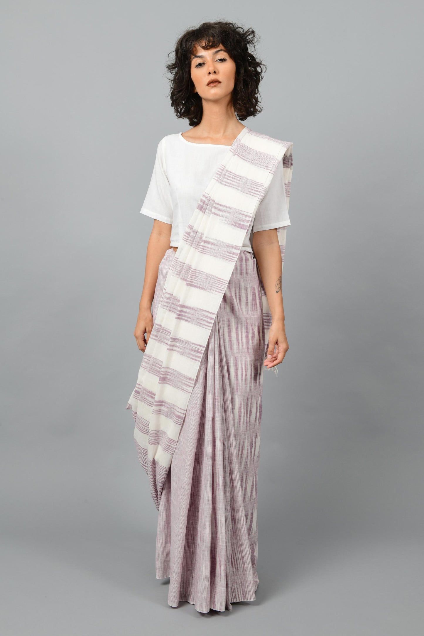 Front pose of a female womenswear fashion model draped in a purple & white space dyed homespun and handwoven cotton saree by Cotton Rack.