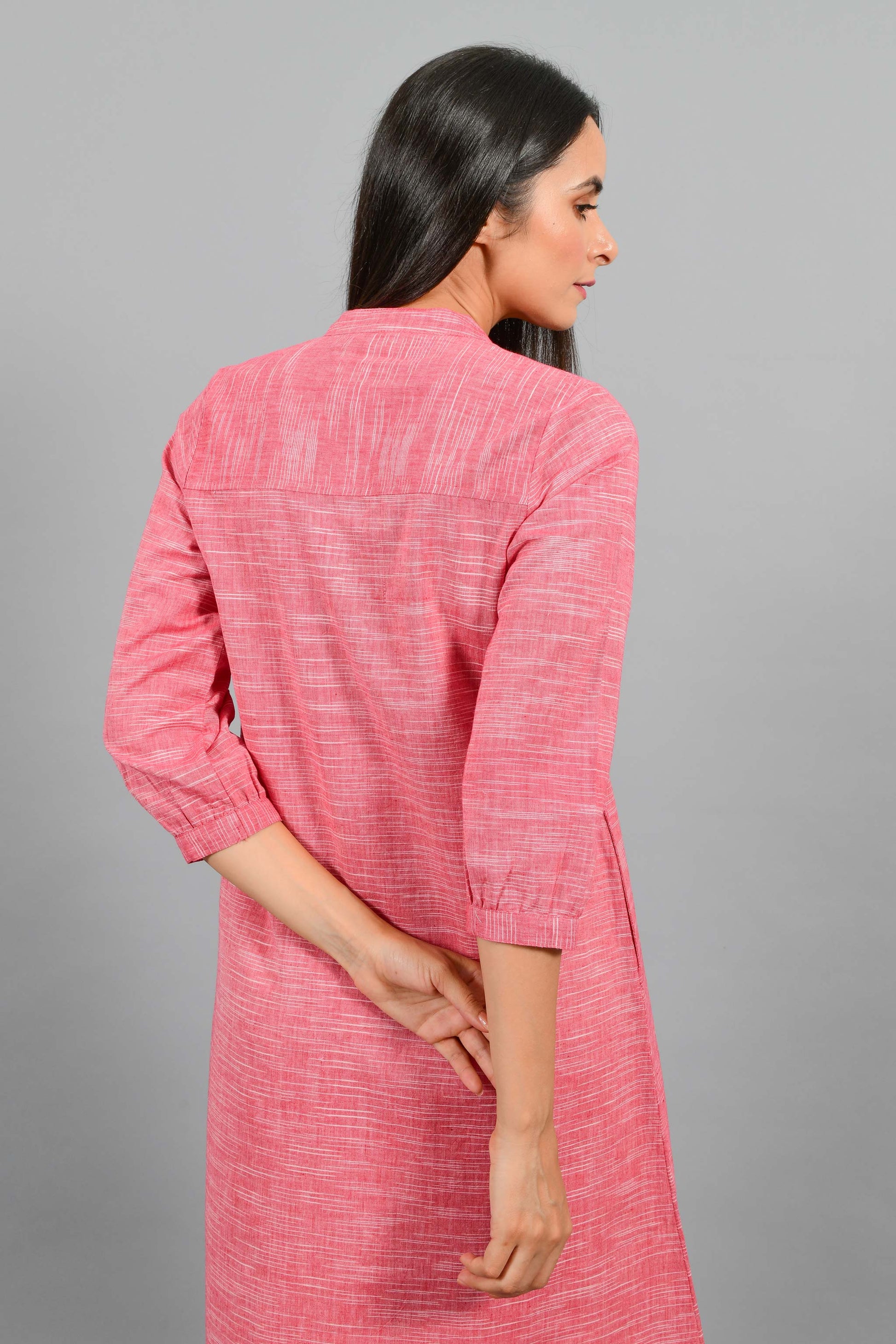 Back close up of an Indian female womenswear fashion model in a red space dyed handspun and handwoven khadi cotton dress with collar and ruffles on front placket by Cotton Rack.