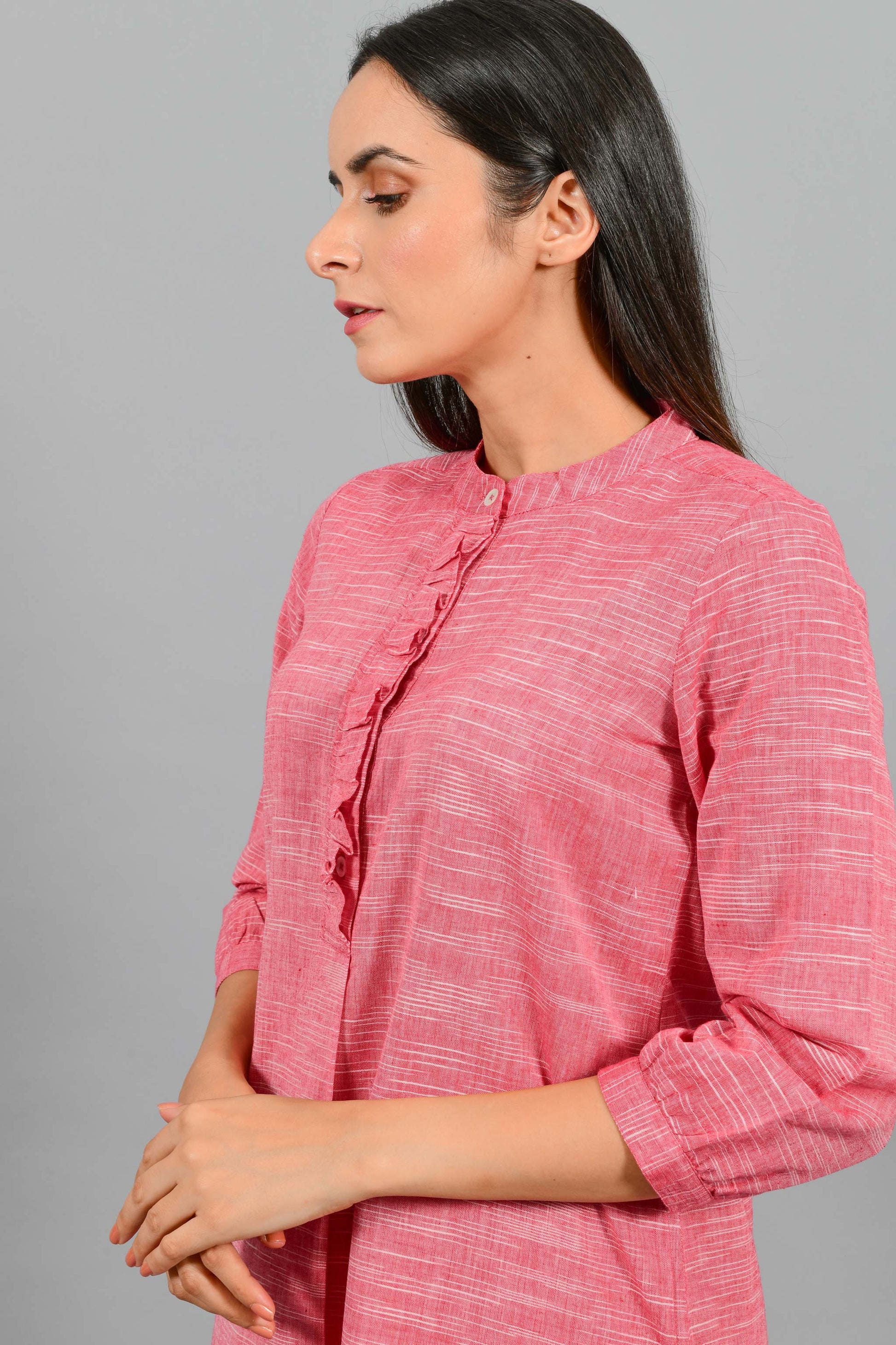 Front portrait of an Indian female womenswear fashion model in a red space dyed handspun and handwoven khadi cotton dress with collar and ruffles on front placket by Cotton Rack.