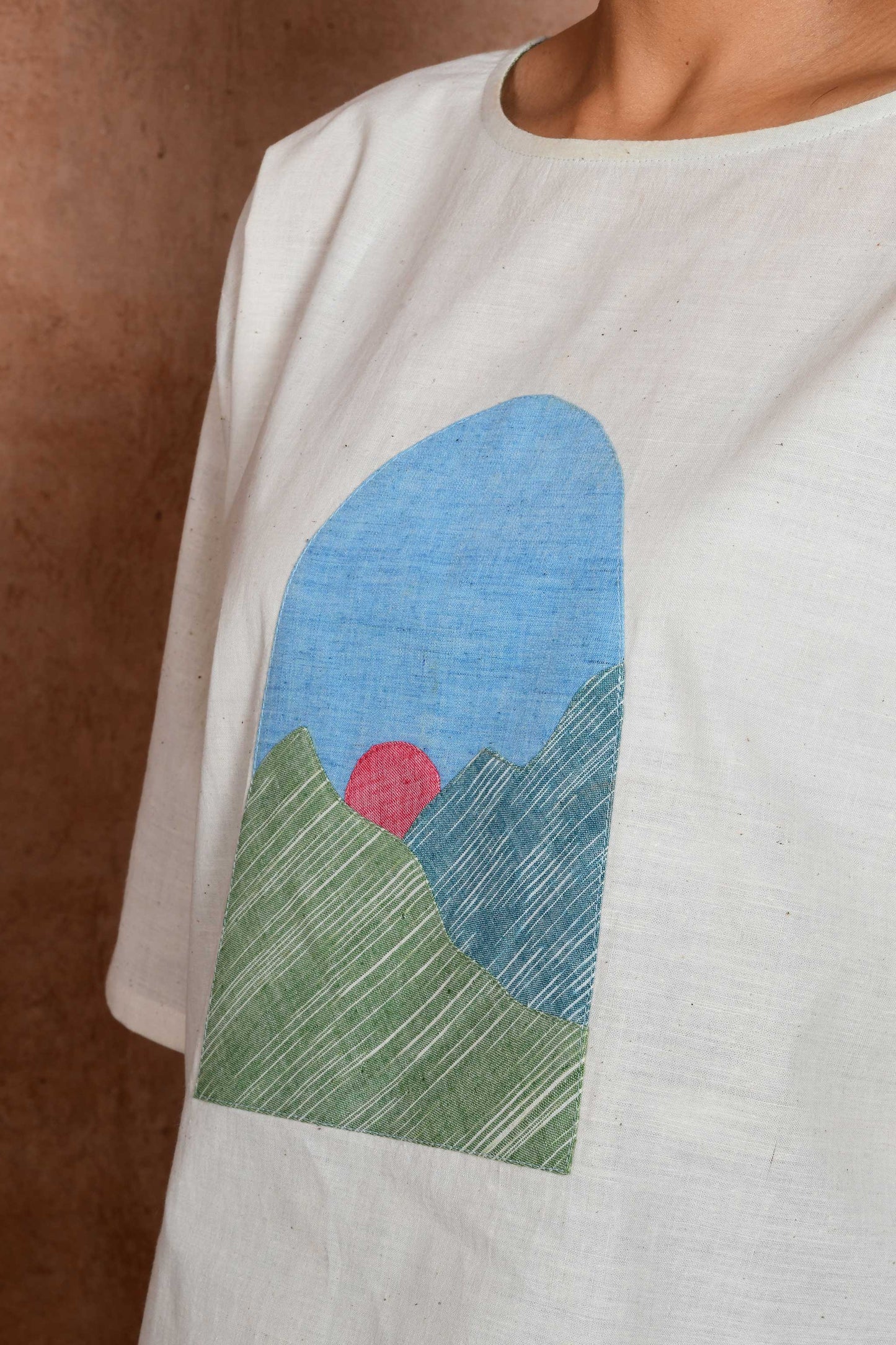 Close up of an applique patch with sunrise with green mountain theme.