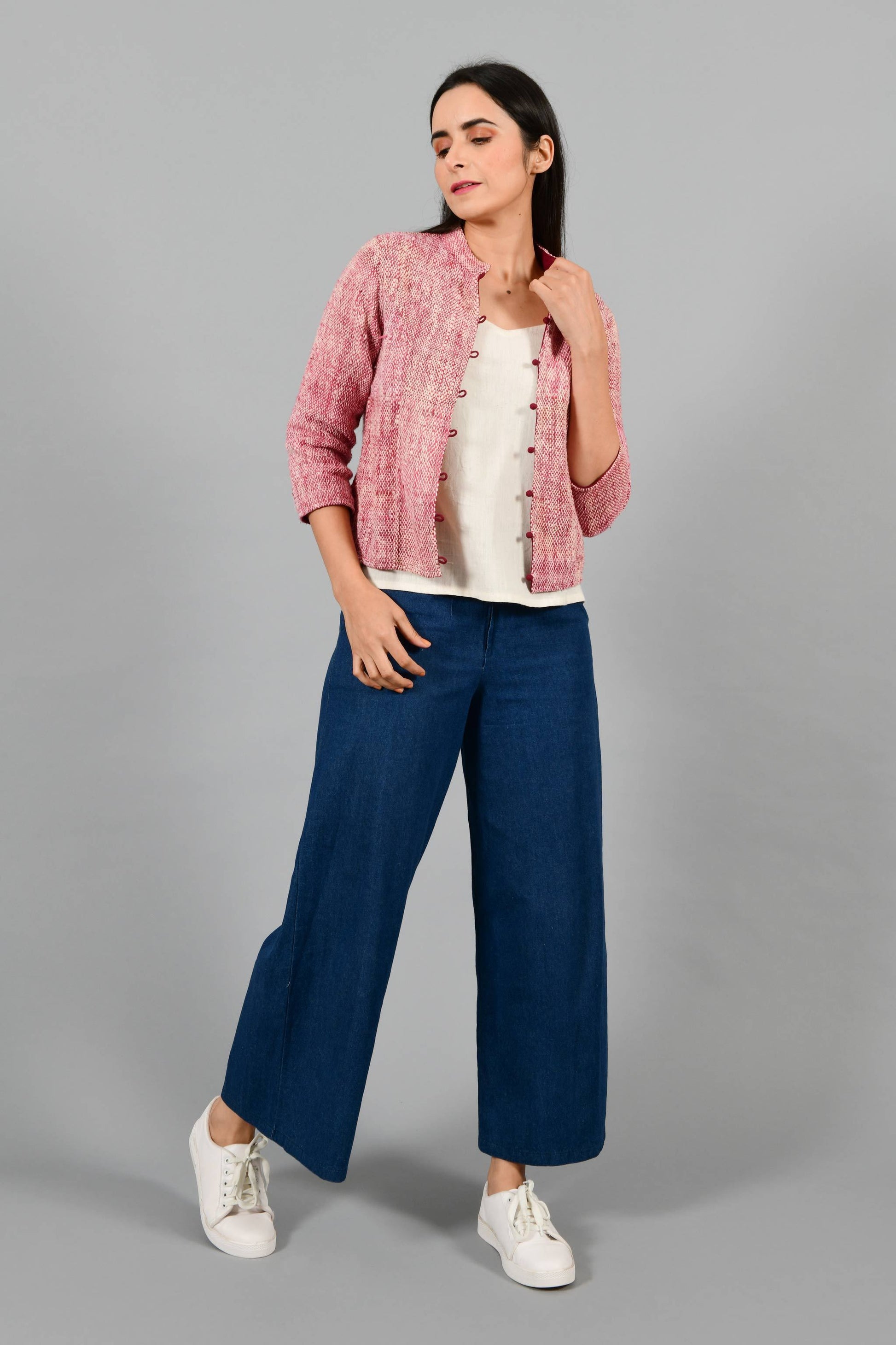 Stylised front pose of an Indian Womenswear female model wearing plum red Gandhi Charkha spun and handwoven khadi buttoned mandarin collar Jacket over an off-white spaghetti and indigo palazzos by Cotton Rack.