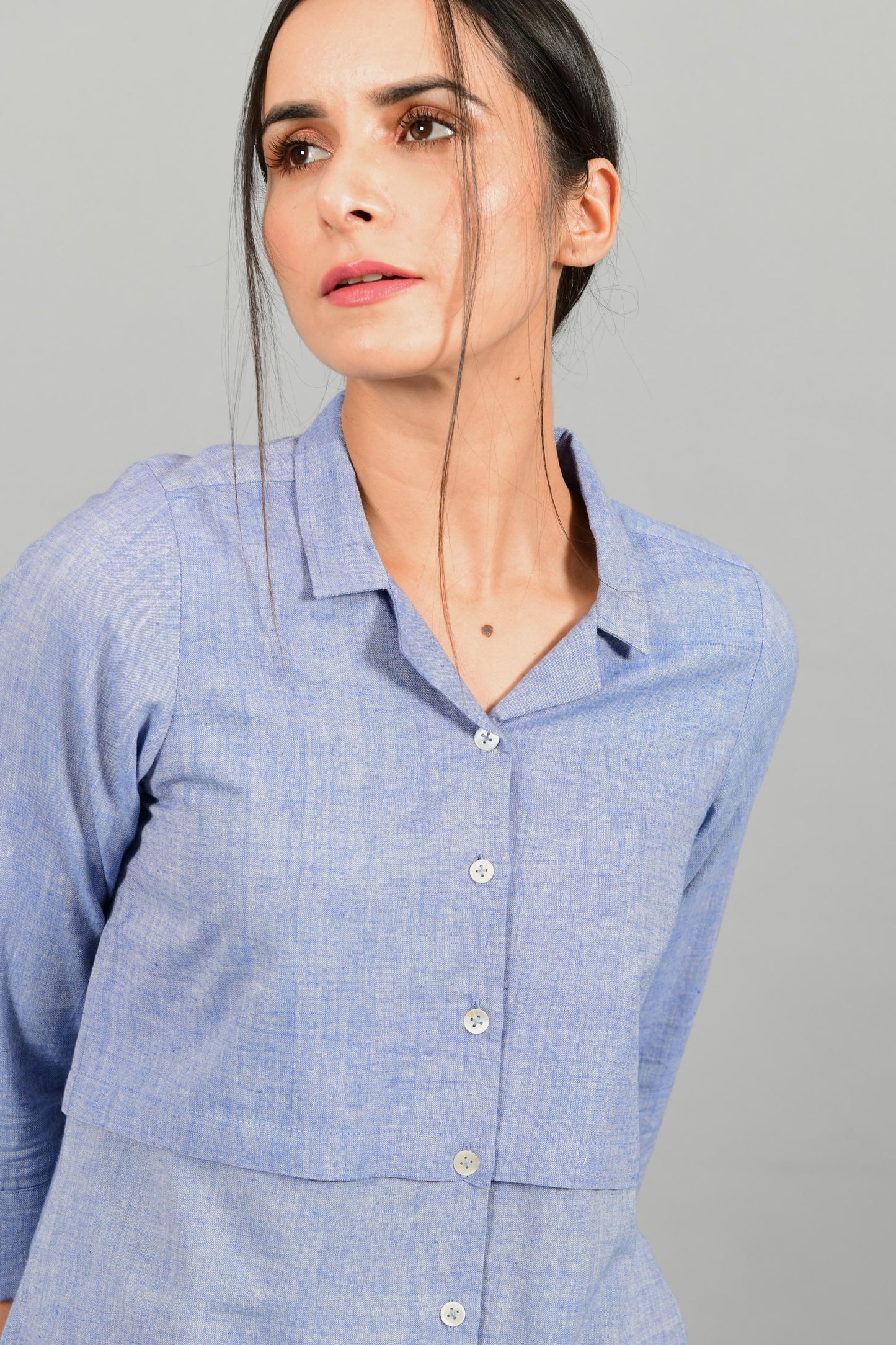 Front close up portrait of an Indian female womenswear fashion model in a blue chambray handspun and handwoven khadi cotton shirt dress by Cotton Rack.