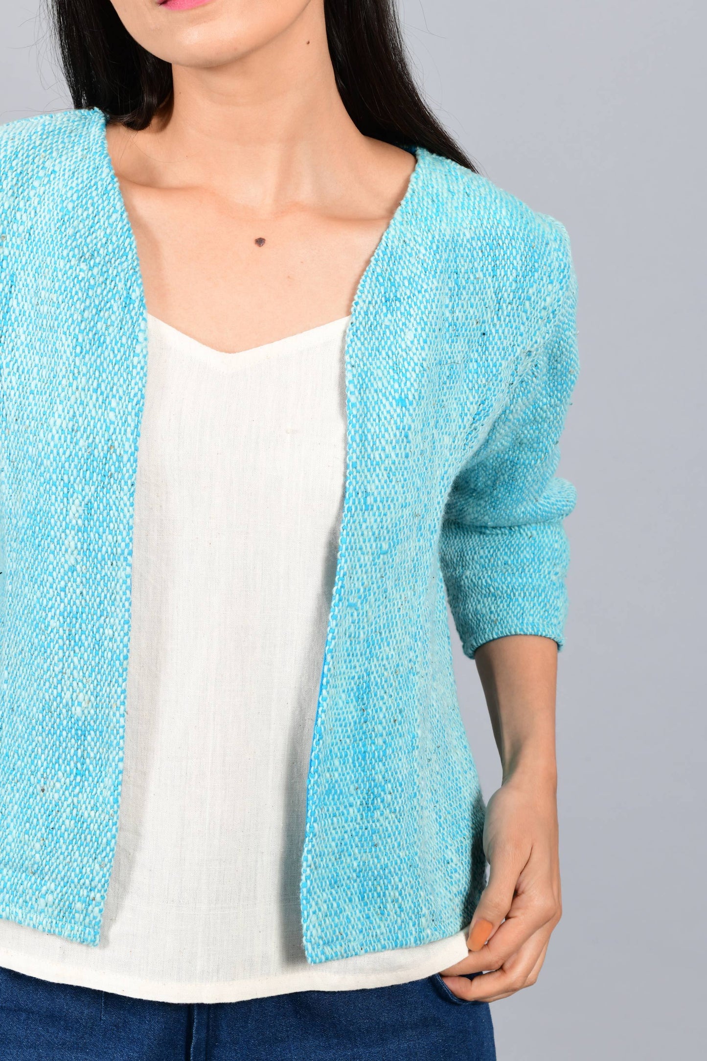 Front close up of an Indian Womenswear female model wearing aqua blue and Gandhi Charkha spun and handwoven khadi Jacket over an off-white spaghetti and indigo palazzos by Cotton Rack.