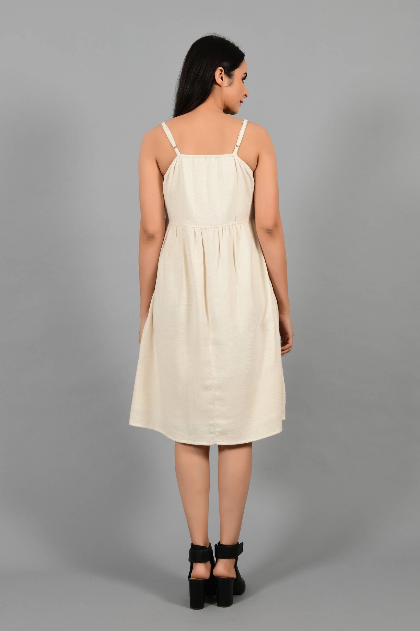 Back pose of an Indian female womenswear fashion model in an off-white Cashmere Cotton Spaghetti Dress made using handspun and handwoven khadi cotton by Cotton Rack.