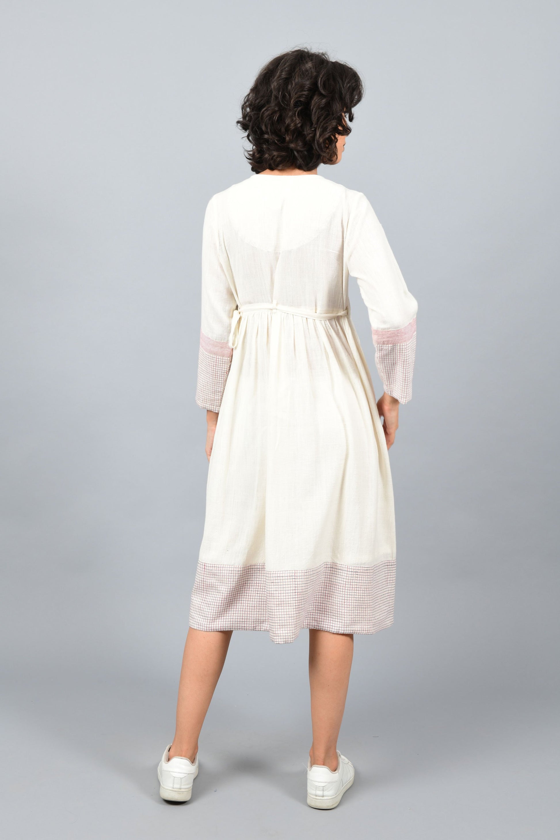 back of a model wearing an angrakha dress printed with red and blue check in the hem and sleeves using brass block printing over handspun handwoven khadi cotton from rajasthan
