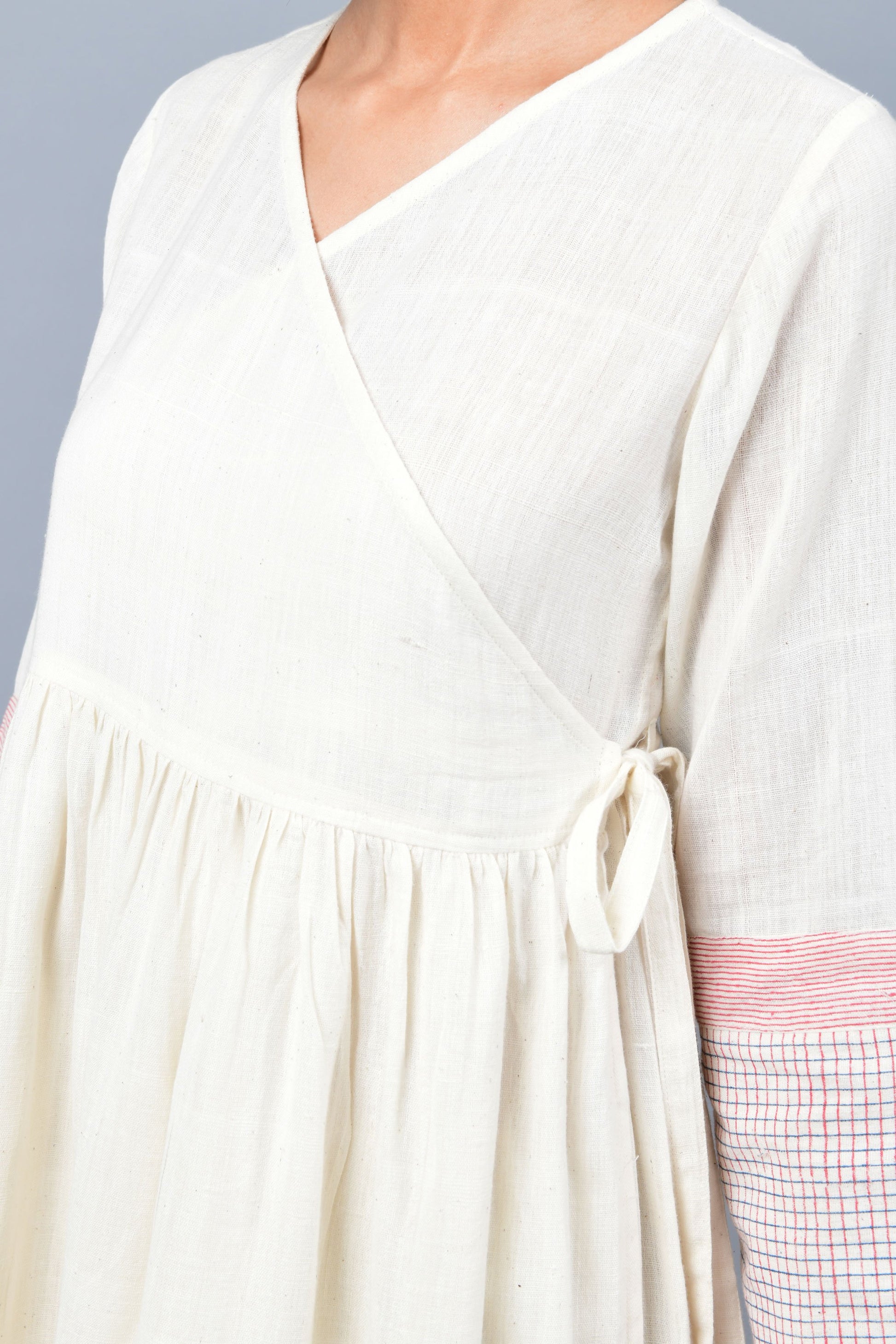 close-up of a model wearing an angrakha dress printed with red and blue check in the hem and sleeves using brass block printing over handspun handwoven khadi cotton from rajasthan