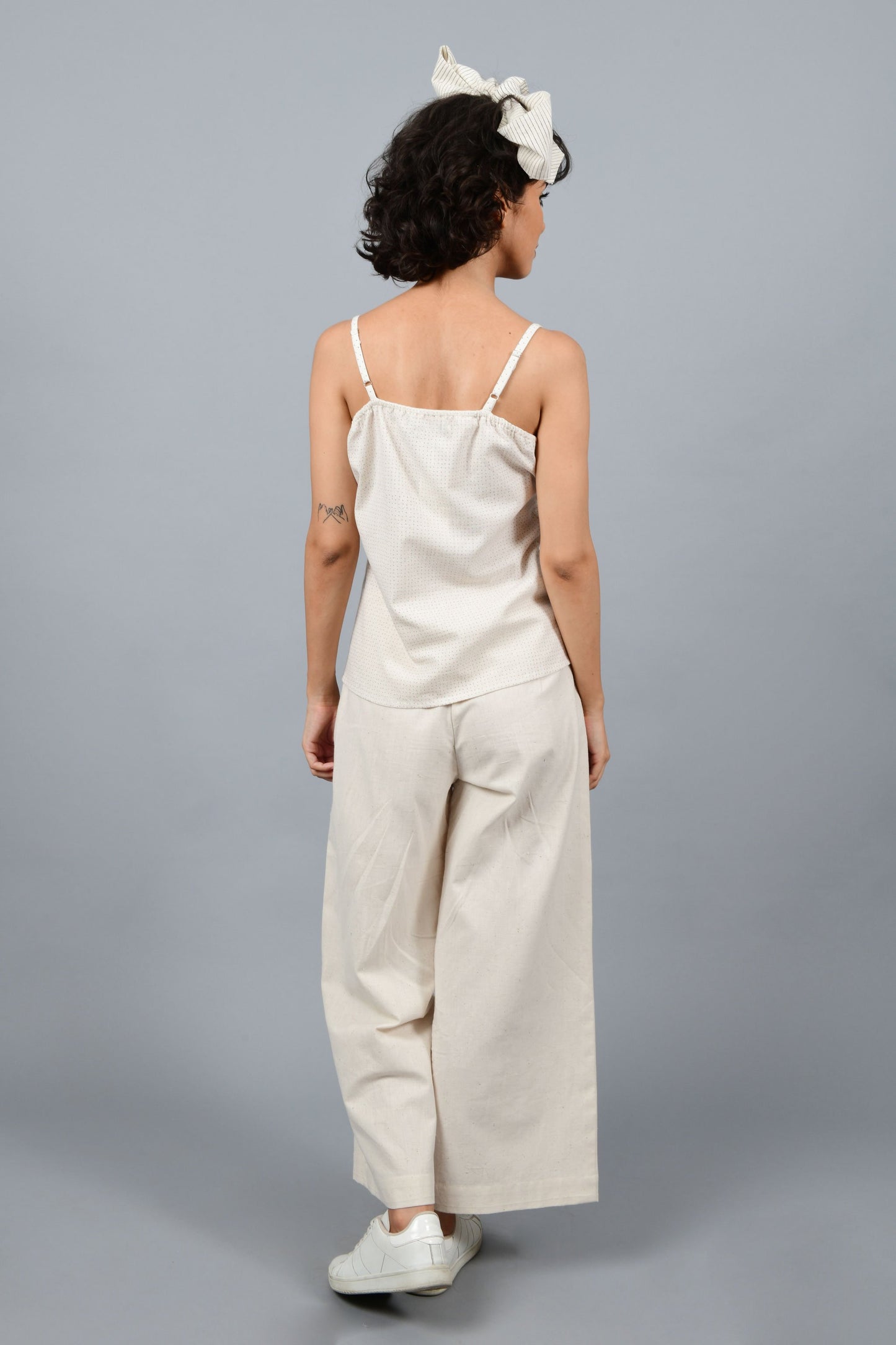 back of a model wearing an spaghetti top printed with red and blue dots stripes using brass block printing over handspun handwoven khadi cotton from maheshwar