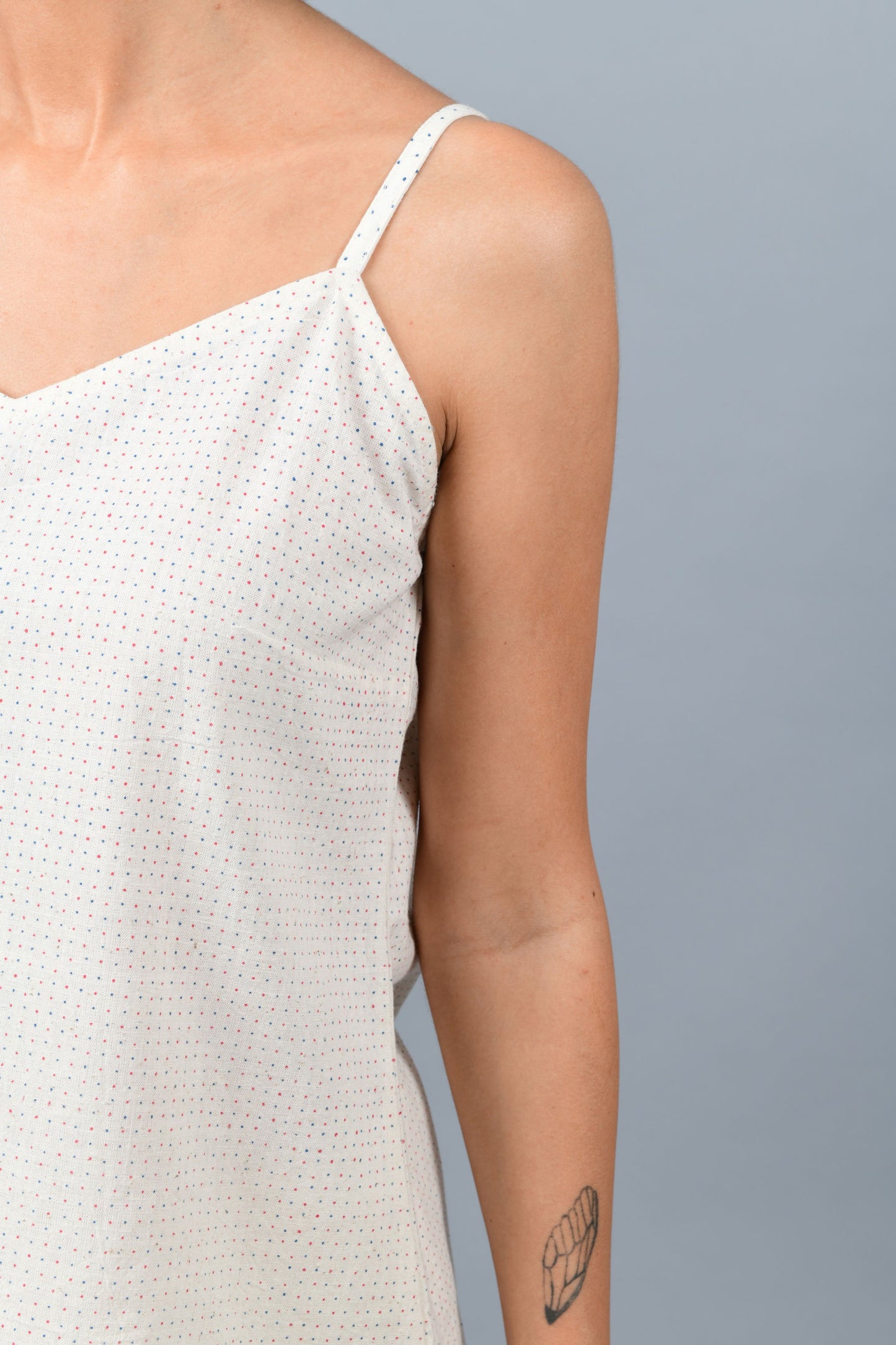 close-up of a model wearing an spaghetti top printed with red and blue dots stripes using brass block printing over handspun handwoven khadi cotton from maheshwar