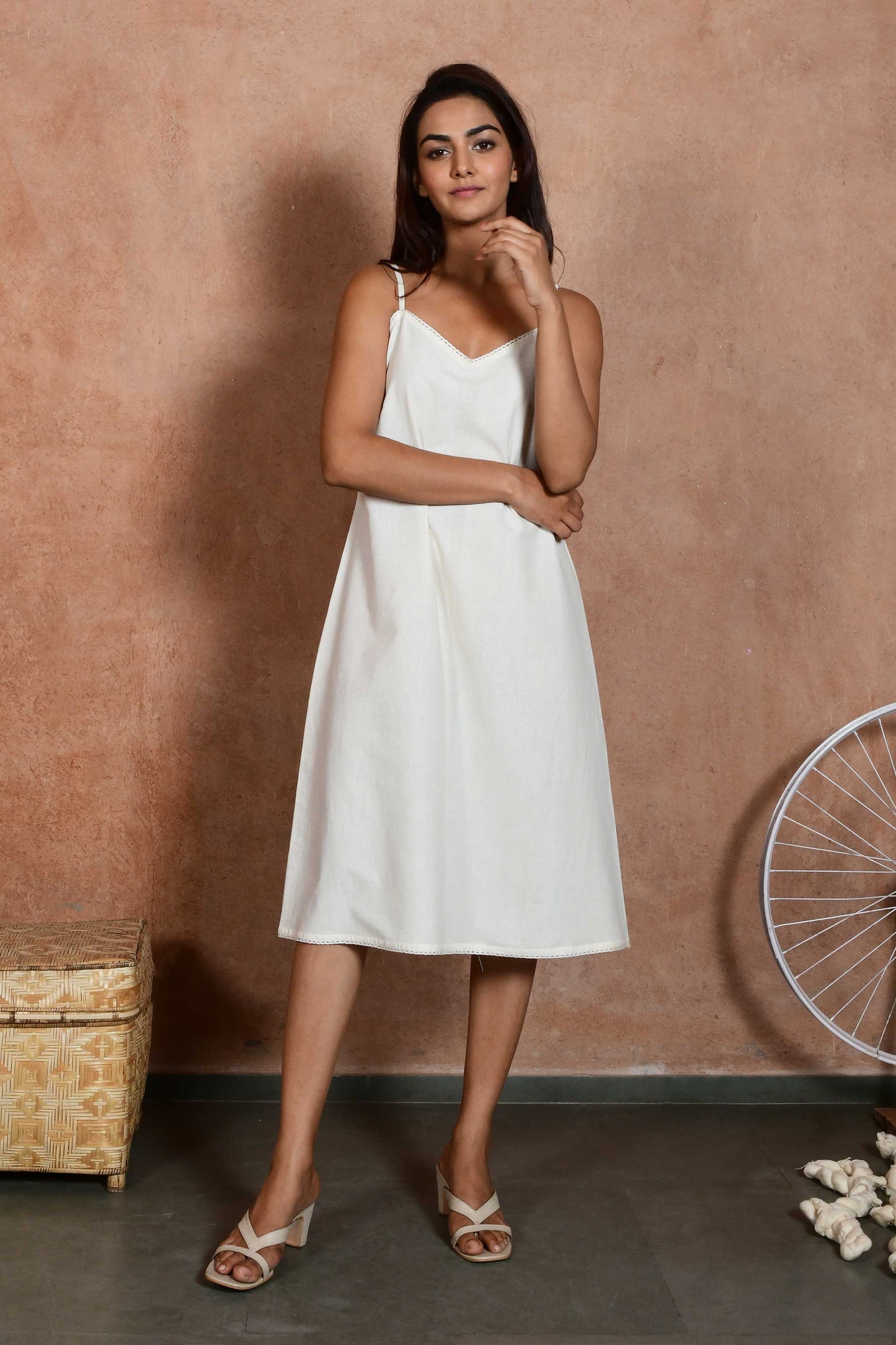 Front pose of an indian model wearing an off white spaghetti slip dress made with handspun handloom cotton.