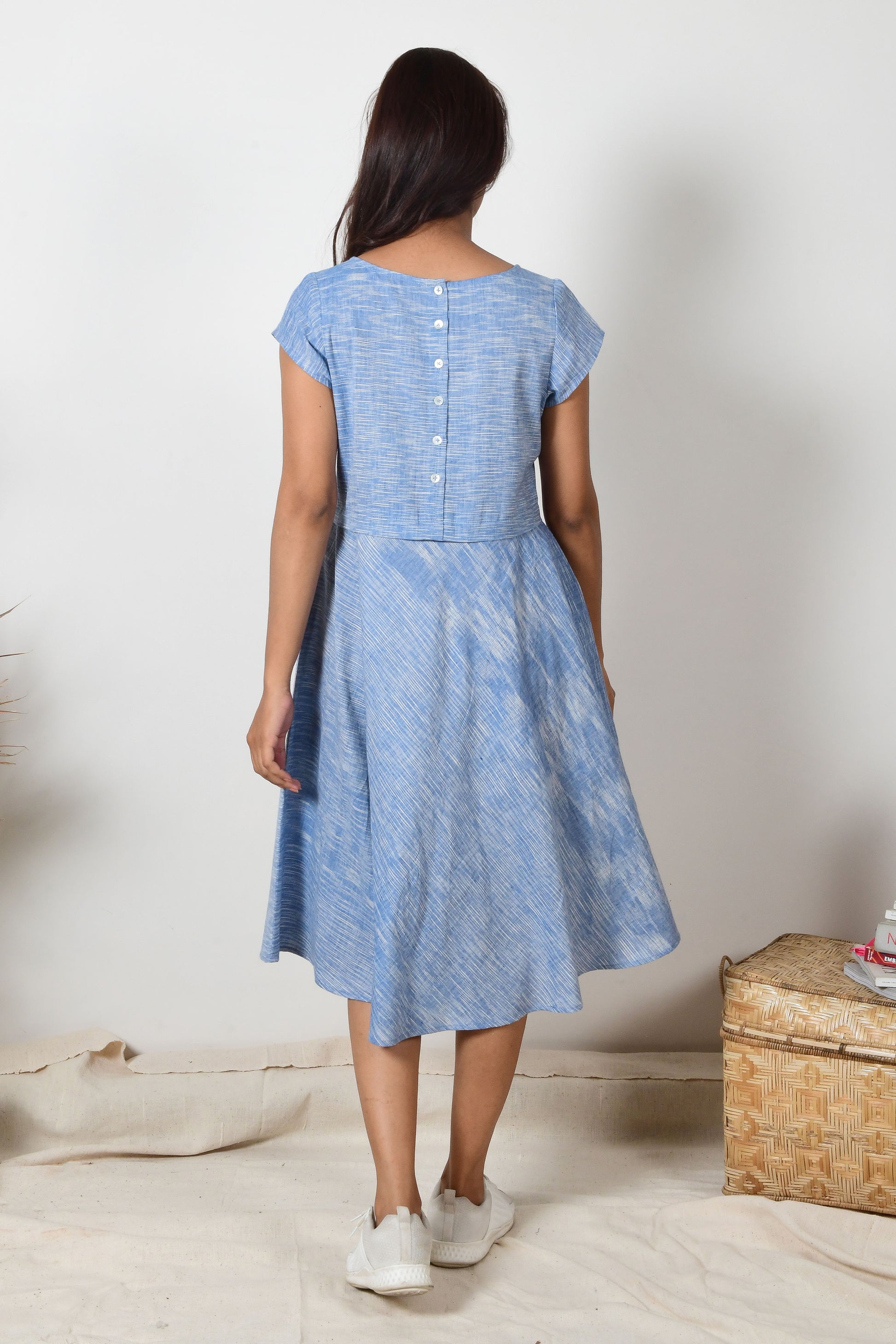 back of an a-line cotton dress of blue colour with button on the bodice worn by an Indian girl with black hair.