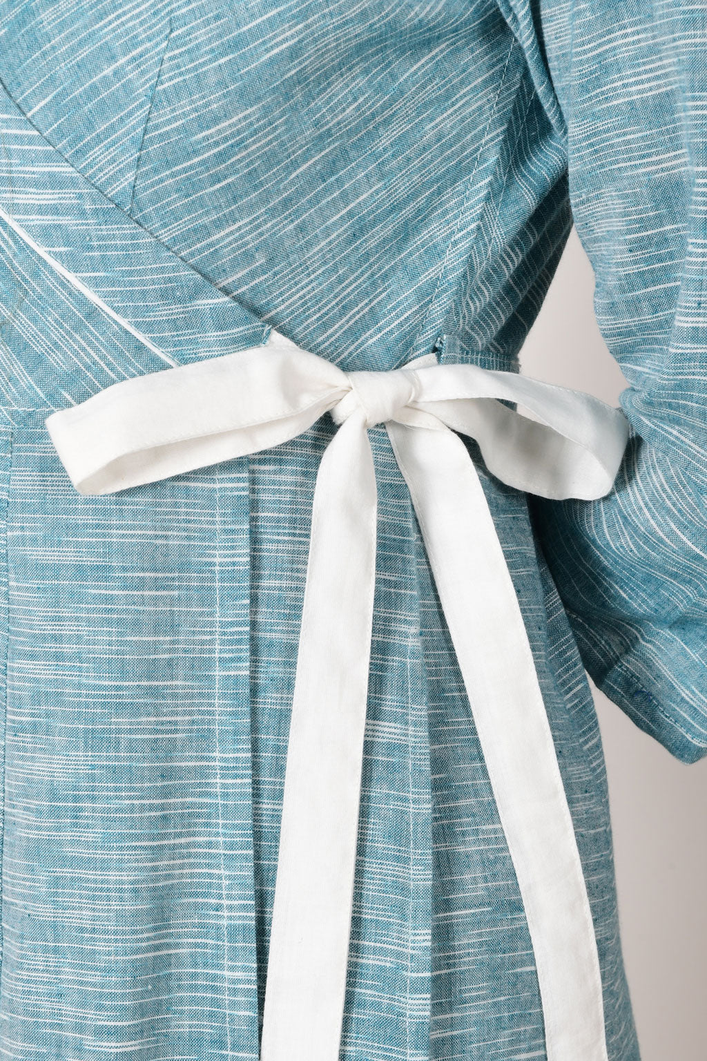 close up of white loop knot on the blue cotton wrap around dress