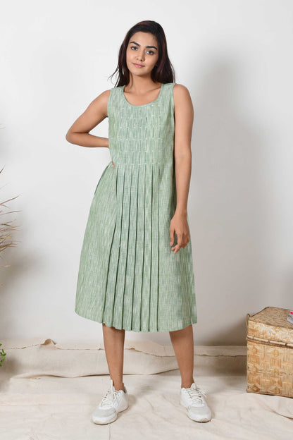 Smiling Indian girl wearing a handspun cotton green sleeveless pleated dress.a