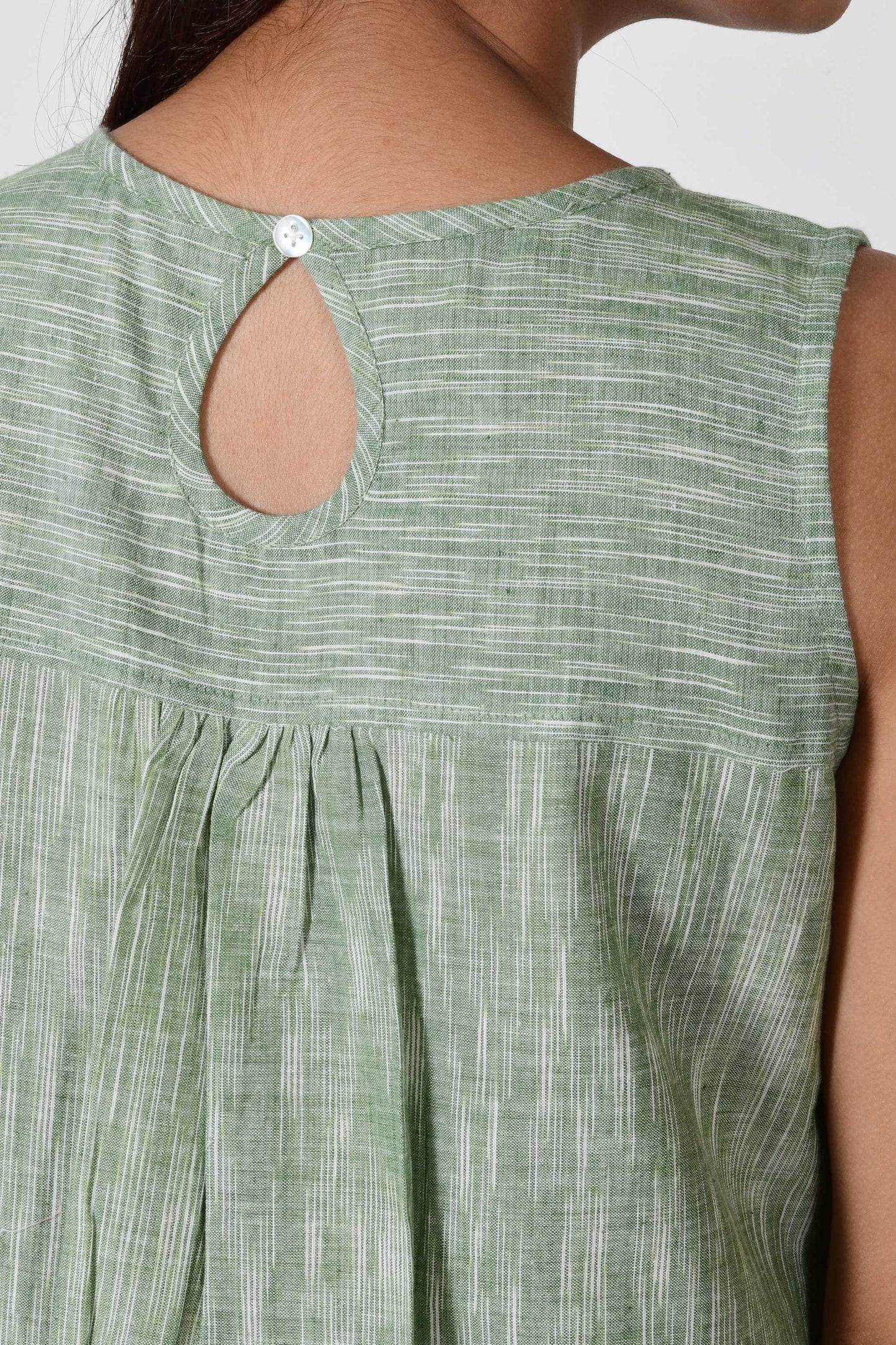 close up of button on the back of the dress made with green texture cotton fabric that is hand spun.