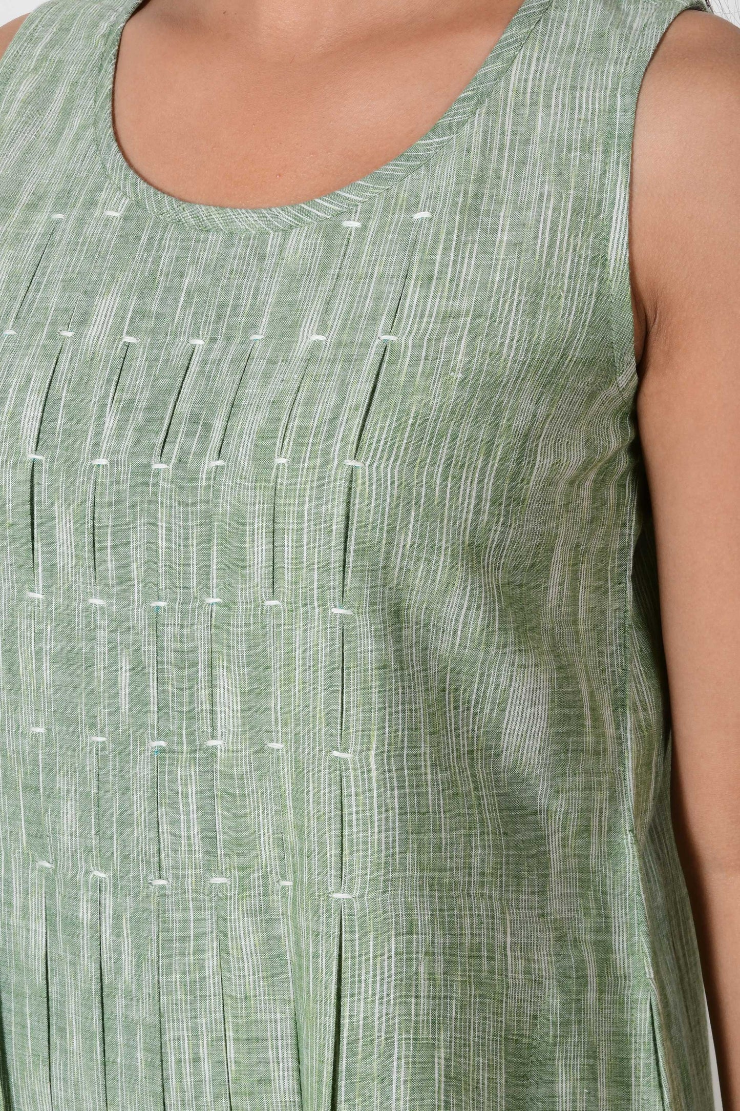 close up of the box pleats on a green textured cotton sleeveless dress.