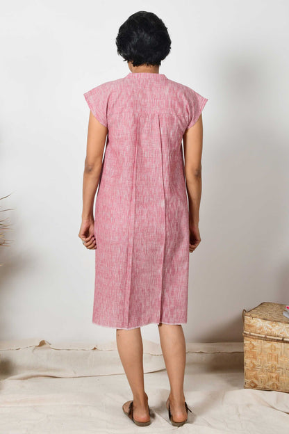 back of brick red cotton midi dress worn by an short haired Indian woman.