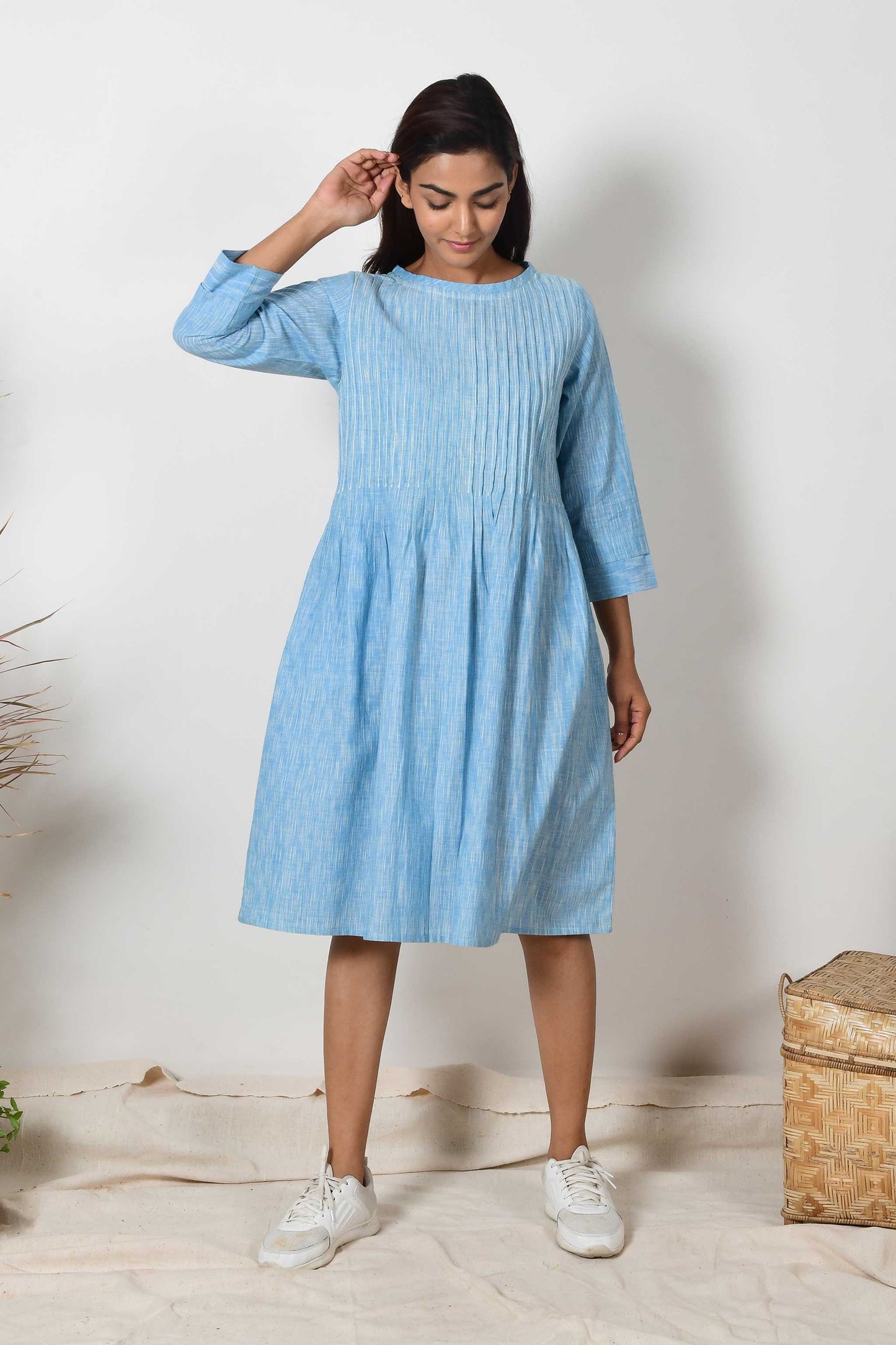 indian girl model wearing a pair of white sneakers and sky blue cotton pleated kurta dress with sleeves.