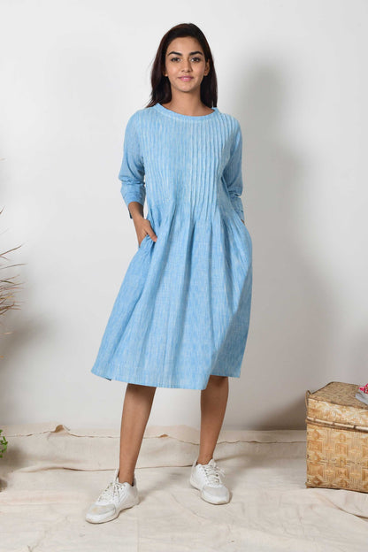 Indian girl with hands in pocket of sky blue cotton pleated dress with a pair of white sneakers