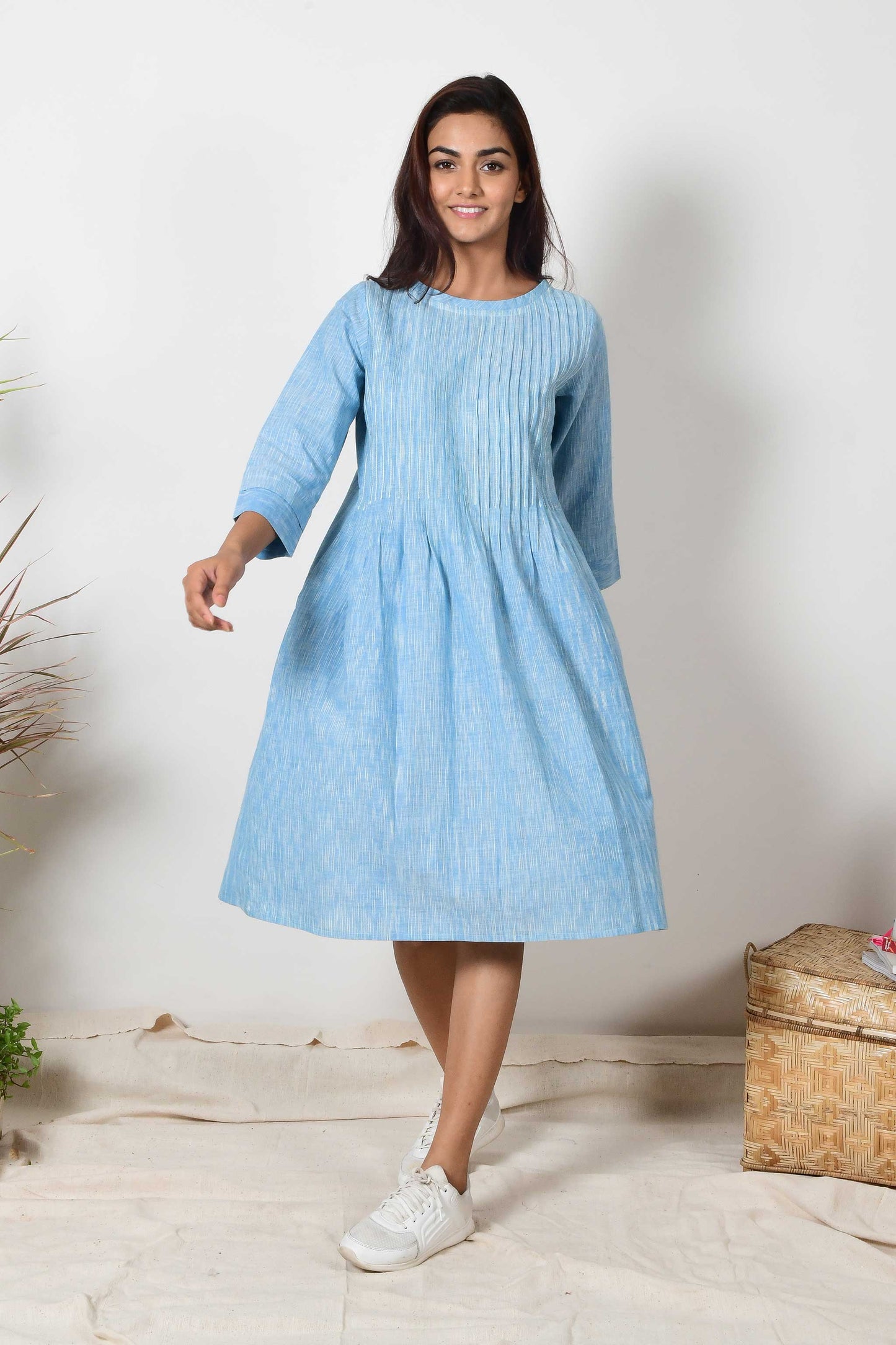 Indian girl smiling and wearing sky blue cotton pleated dress with a pair of white sneakers