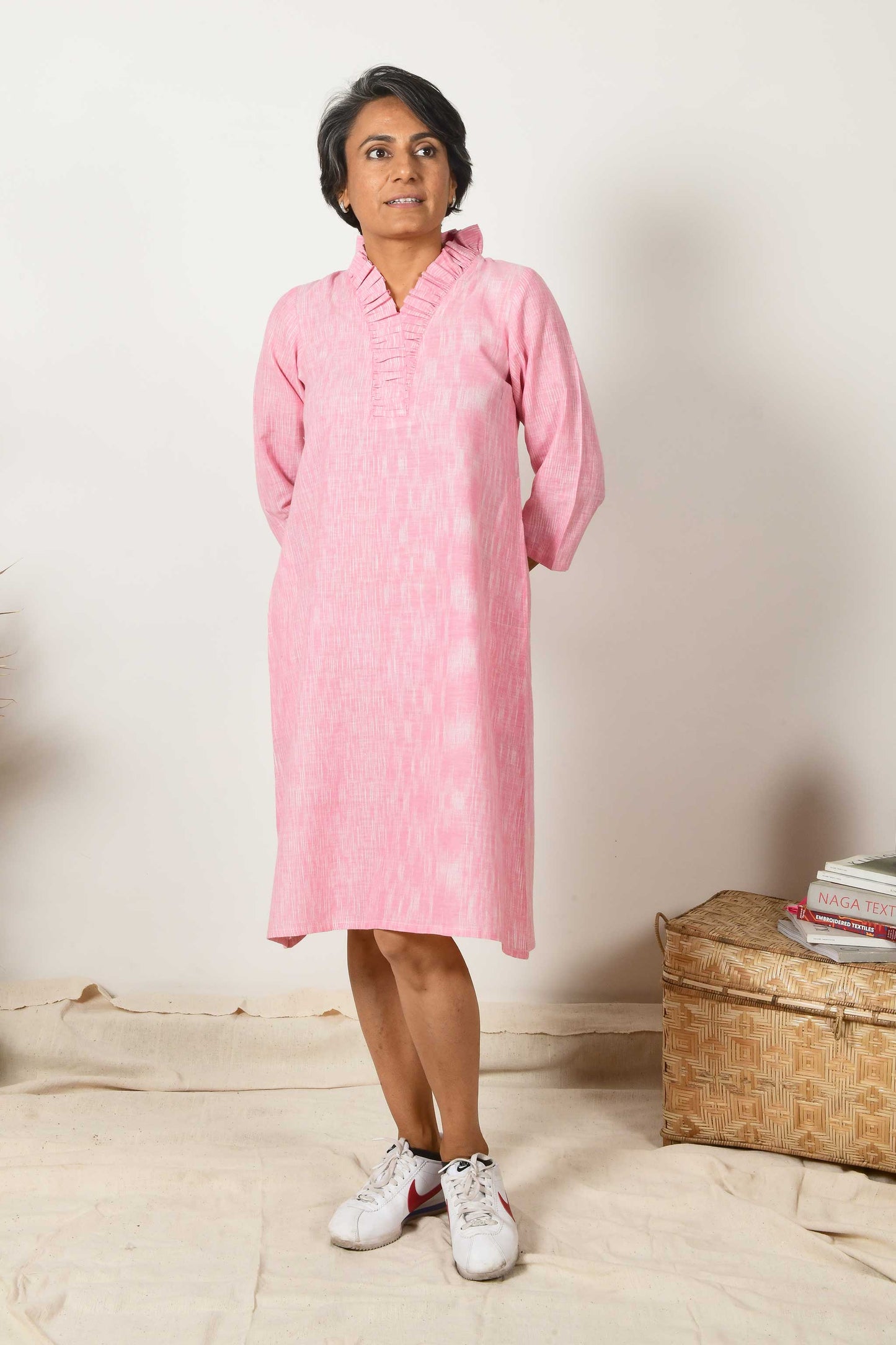 short haired indian woman wearing baby pink flared neck Kurta dress made using hand spun hand woven cotton.