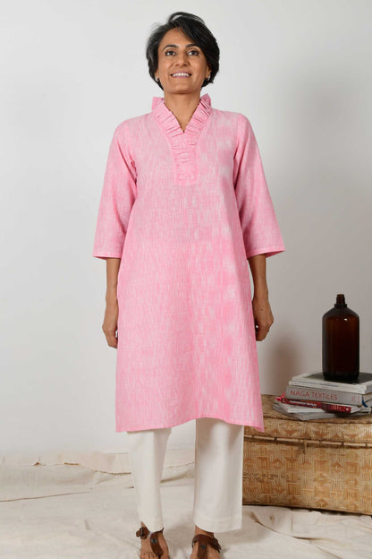short haired indian woman wearing baby pink flared neck Kurta dress made using hand spun hand woven cotton.