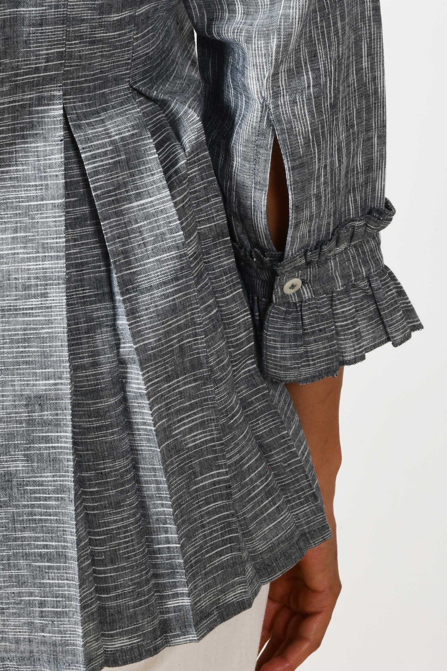 close up of the ruffled sleeve and cuff placket of a grey cotton top.