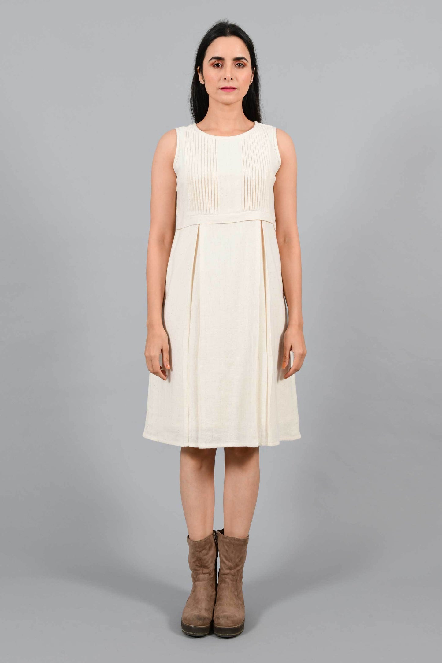 Front pose of an Indian female womenswear fashion model in an off-white Cashmere Cotton Pleated Dress made using handspun and handwoven khadi cotton by Cotton Rack.