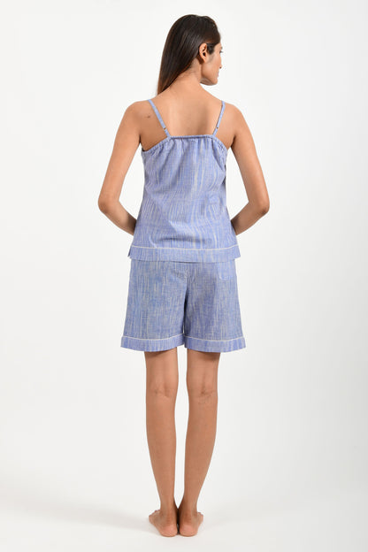 Back pose of an Indian female womenswear fashion model in azo-free space dyed blue handspun and handwoven khadi cotton spaghetti top and boxers by Cotton Rack.
