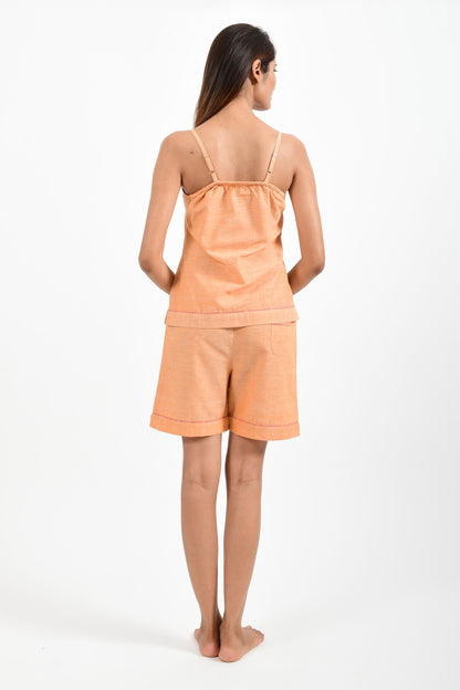 Back pose of an Indian female womenswear fashion model in azo-free dyed orange chambray handspun and handwoven khadi cotton spaghetti top and boxers by Cotton Rack.