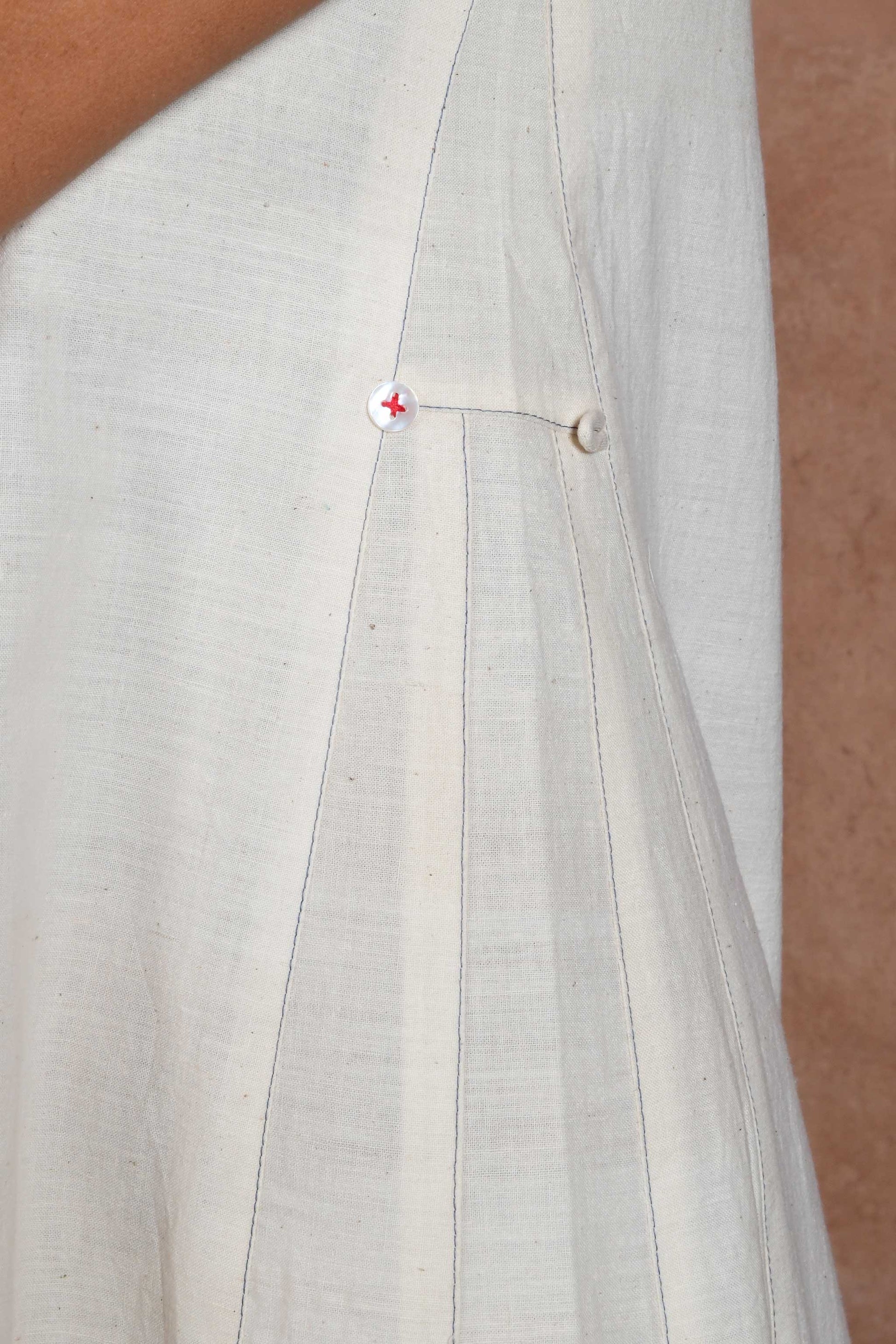 close up of side seam details with contrasting stitch lines and white button with red thread.