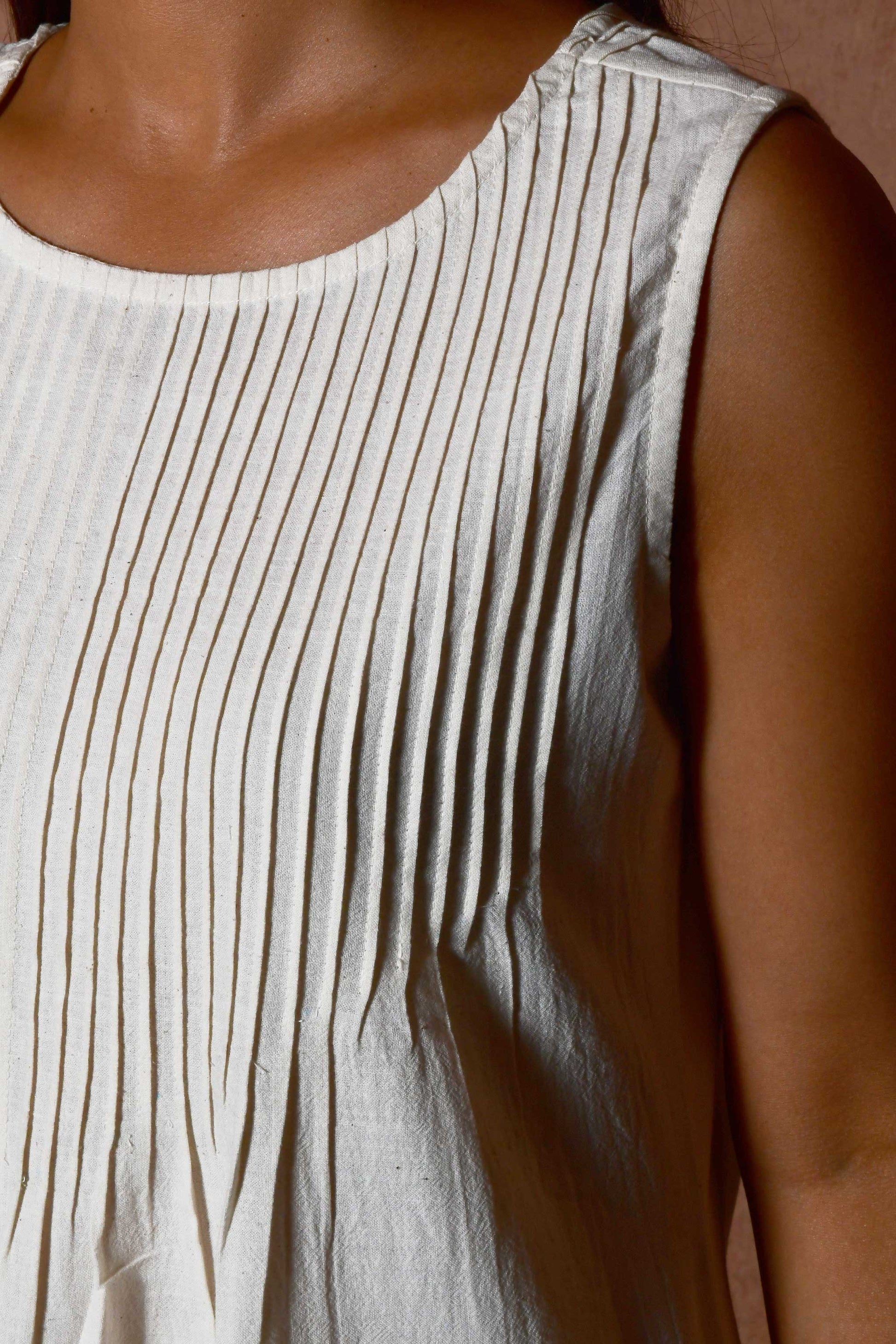 Close up of the knife pleats on the front of the sleeveless dress.