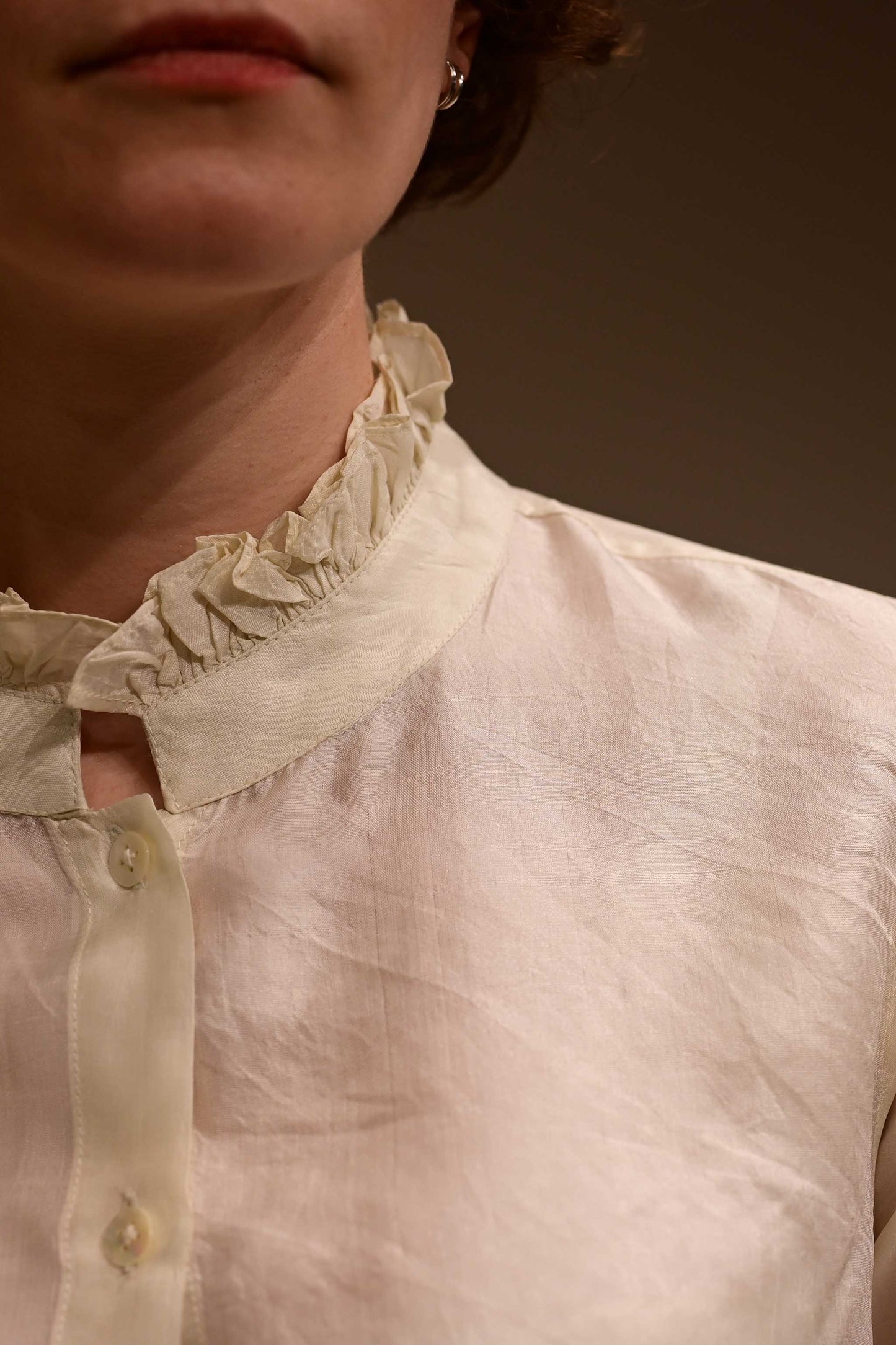 Closse up of the ruffled collar of ivory white silk shirt that is hand reeled and hand spun in India.