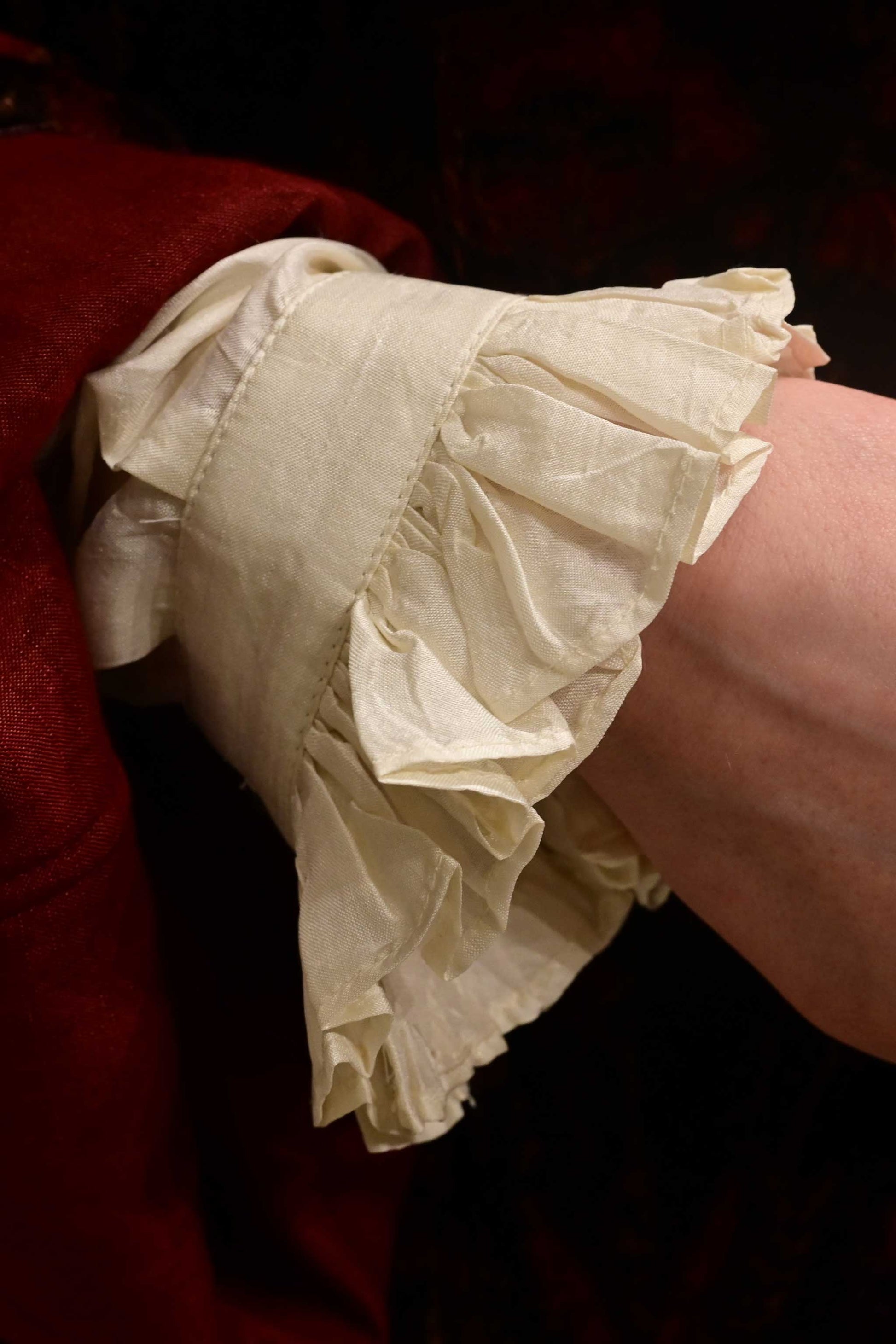 Close up of the ruffled cuff of a natural ivory white silk shirt that is artisanally made using ethically sourced hand reeled and hand spun silk from India.