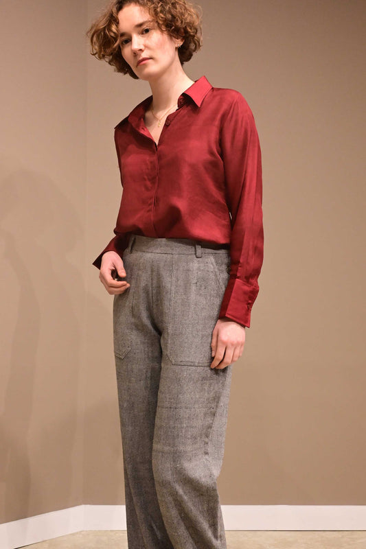 Front profile of a caucasian female model wearing a collared silk shirt in wine red color that is made from ethically sourced hand reeled and hand spun Indian silk.