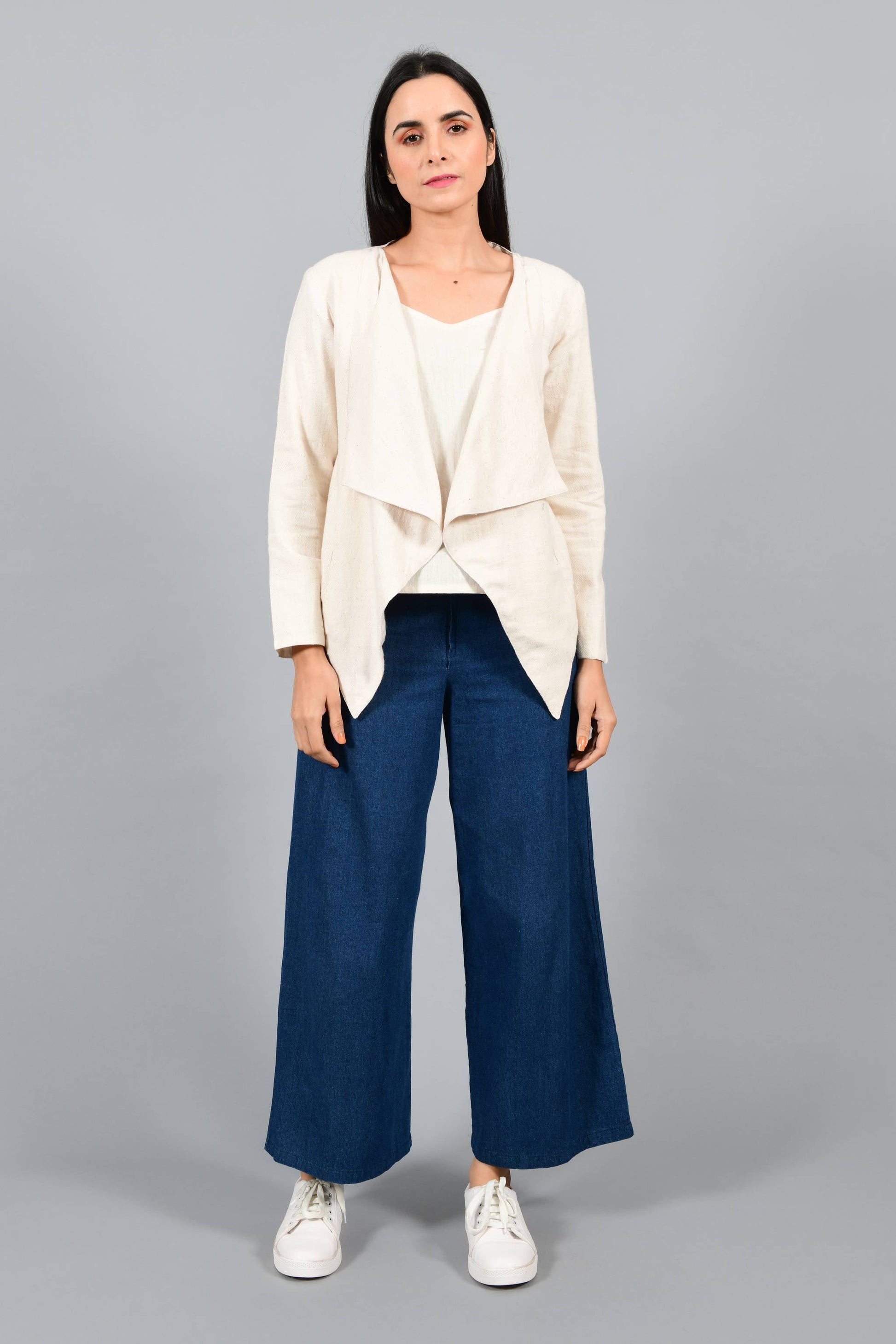 Front pose of an Indian female womenswear fashion model in a short off-white Cashmere Cotton jacket-shrug with extra wide lapels, made using handspun and handwoven khadi cotton by Cotton Rack.