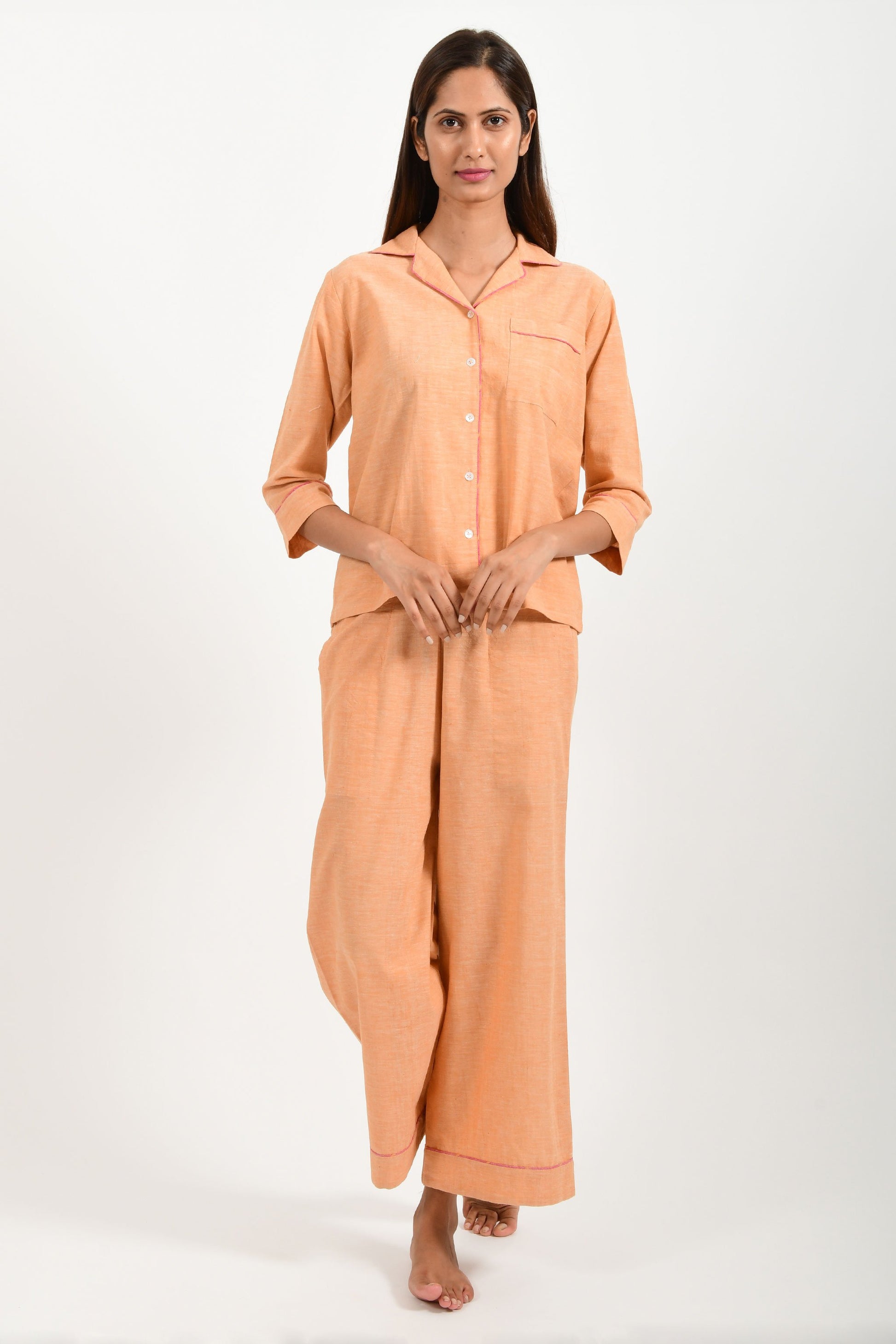 Front pose of an Indian female womenswear fashion model in azo-free dyed handspun and handwoven khadi cotton nightwear pyjama & shirt in orange chambray by Cotton Rack.