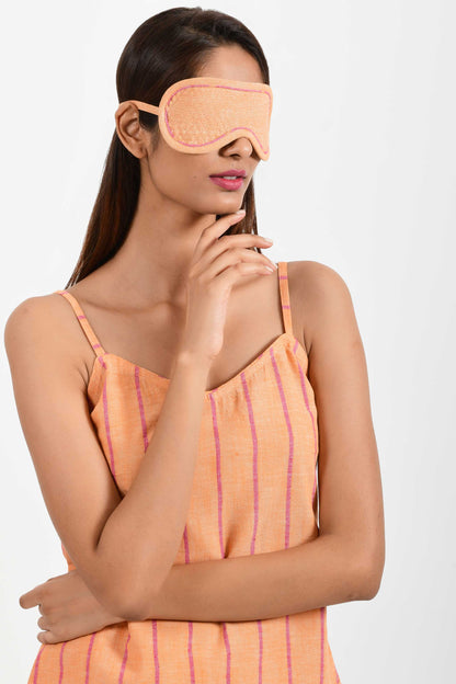 Front portrait of an Indian female womenswear fashion model wearing a orange chambray handspun and handwoven khadi cotton eye mask by Cotton Rack.