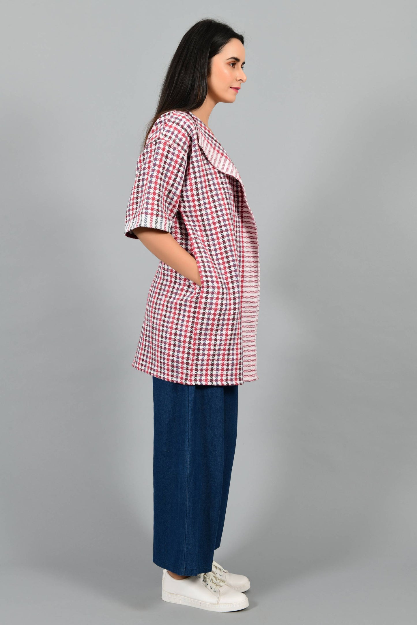 Side pose of an Indian Womenswear female model wearing Red and Blue handspun and handwoven khadi long Jacket over an off-white cashmere cotton dress by Cotton Rack.