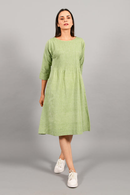 Front pose of an Indian female womenswear fashion model in a olive green chambray handspun and handwoven khadi cotton dress-kurta with pintucks on front by Cotton Rack.