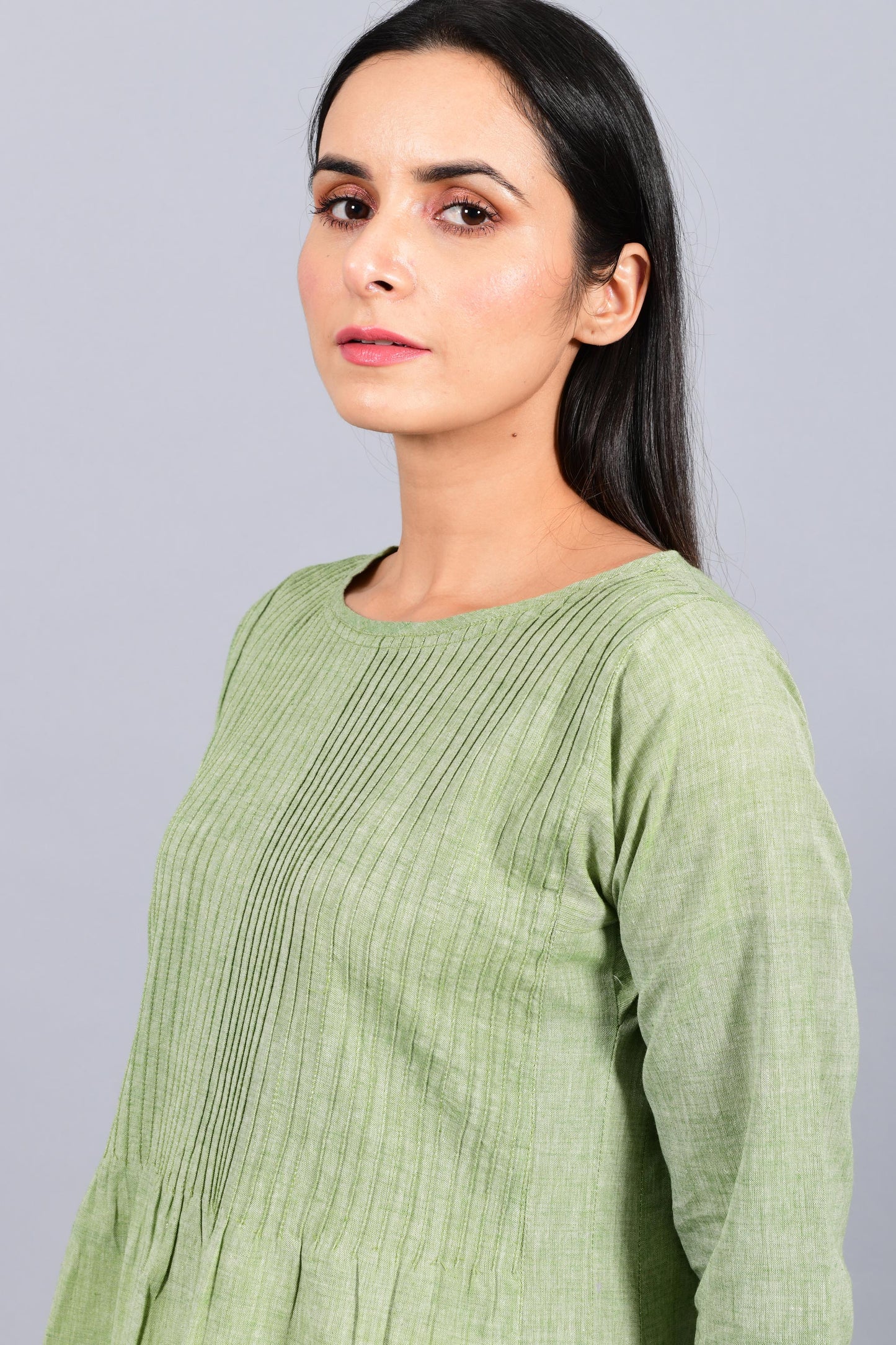 Close up portrait of an Indian female womenswear fashion model in a olive green chambray handspun and handwoven khadi cotton dress-kurta with pintucks on front by Cotton Rack.